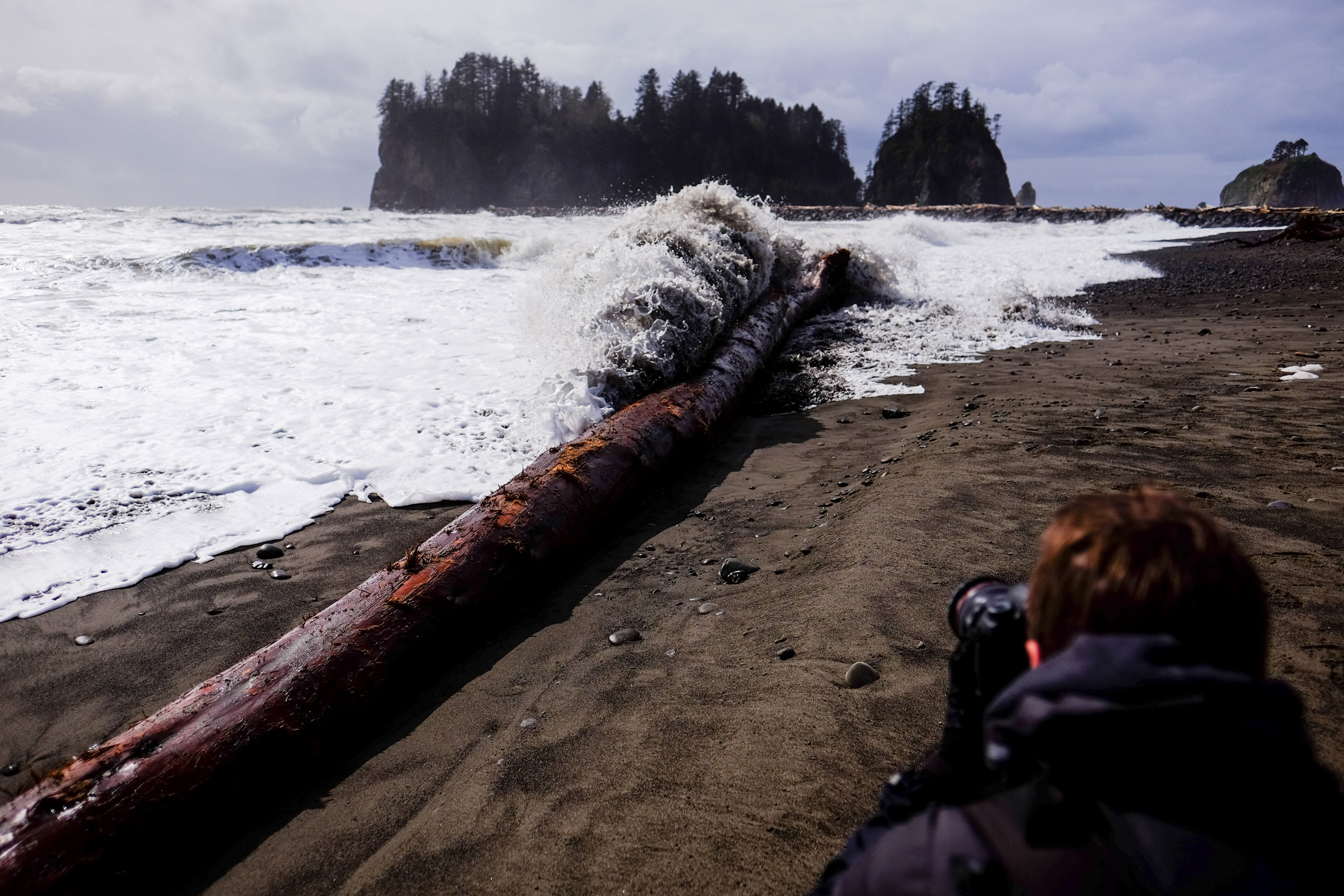  When two photographers try to get shots of a wave hit a log... and then having to run back to avoid getting soaked. 