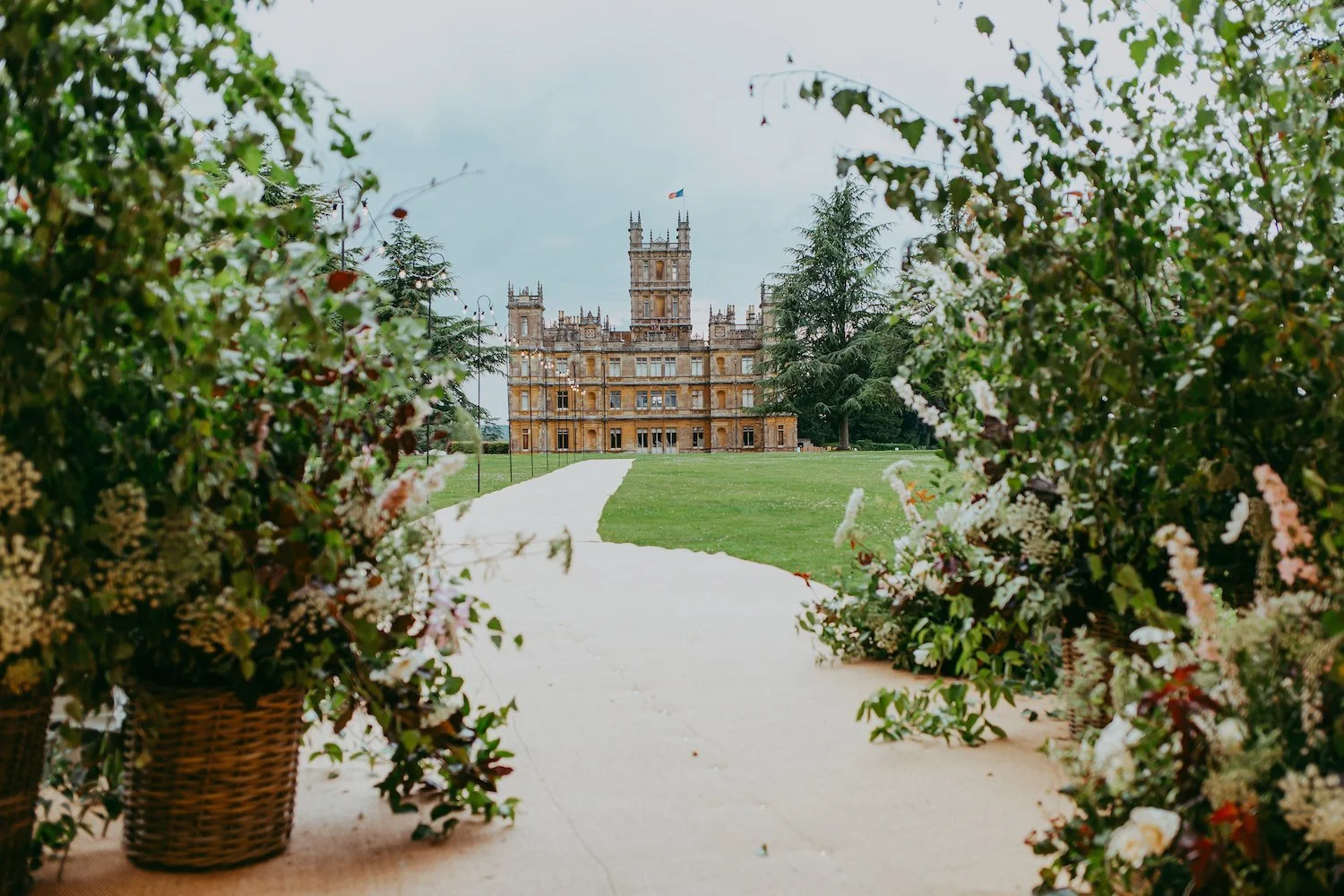Highclere Castle as viewed from the wedding marquee on the lawn. Entrance framed with huge birch branches and plenty of seasonal British flowers