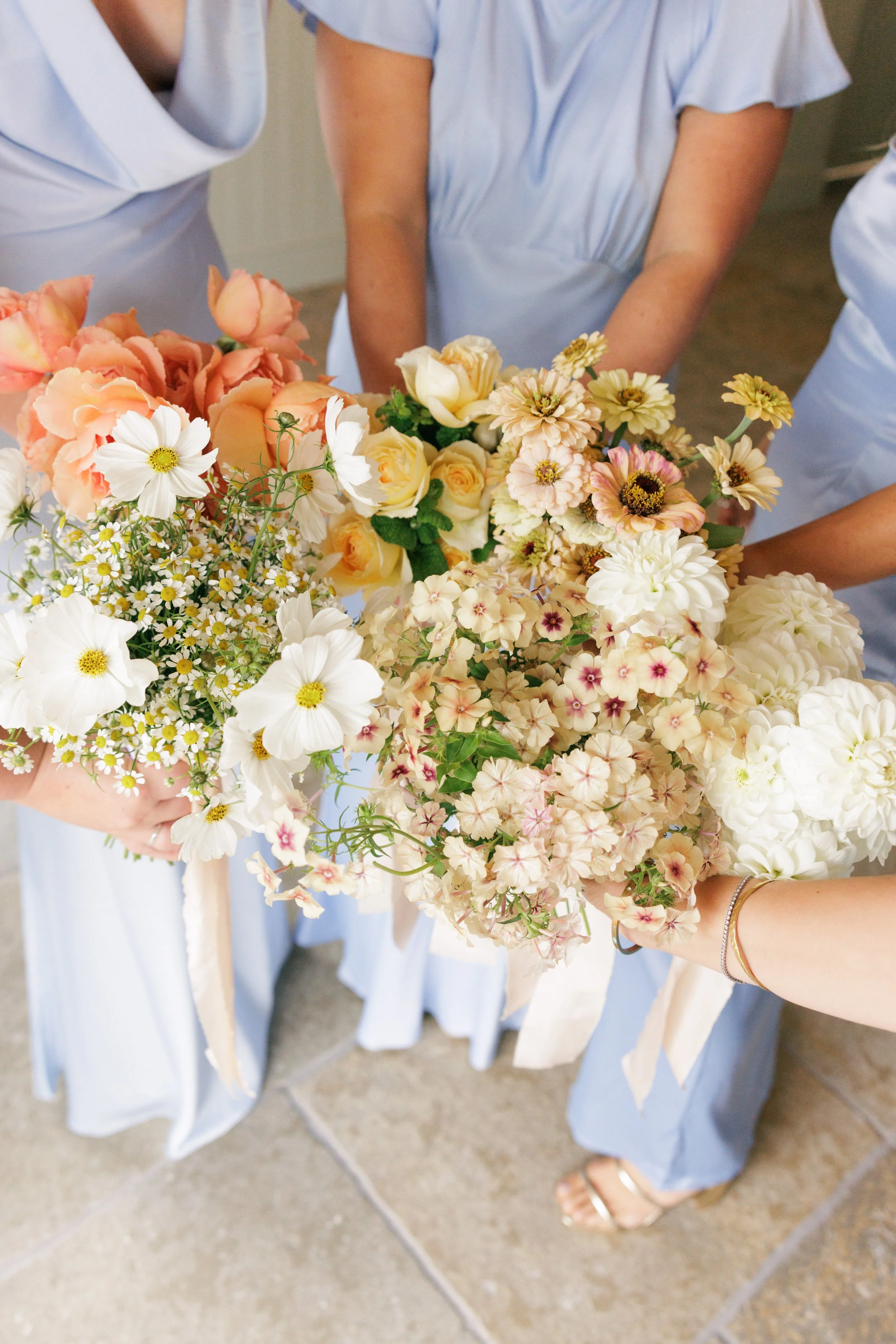 Bride in stylish white dress and groom in black tie, with english flowers bridal bouquet in soft pastels and pops of raspberry. Standing in the Dutch Barn at Silchester Farm, Hampshire, framed by floral columns or broken arch with plenty of flowers.