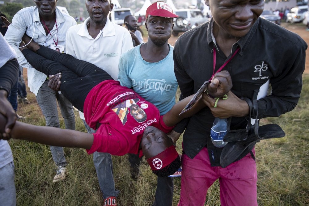  Supporters of Bobi Wine carry an injured man whilst being teargassed as Wine campaigns in central Uganda on November 30, 2020 in Mukono, Uganda. 