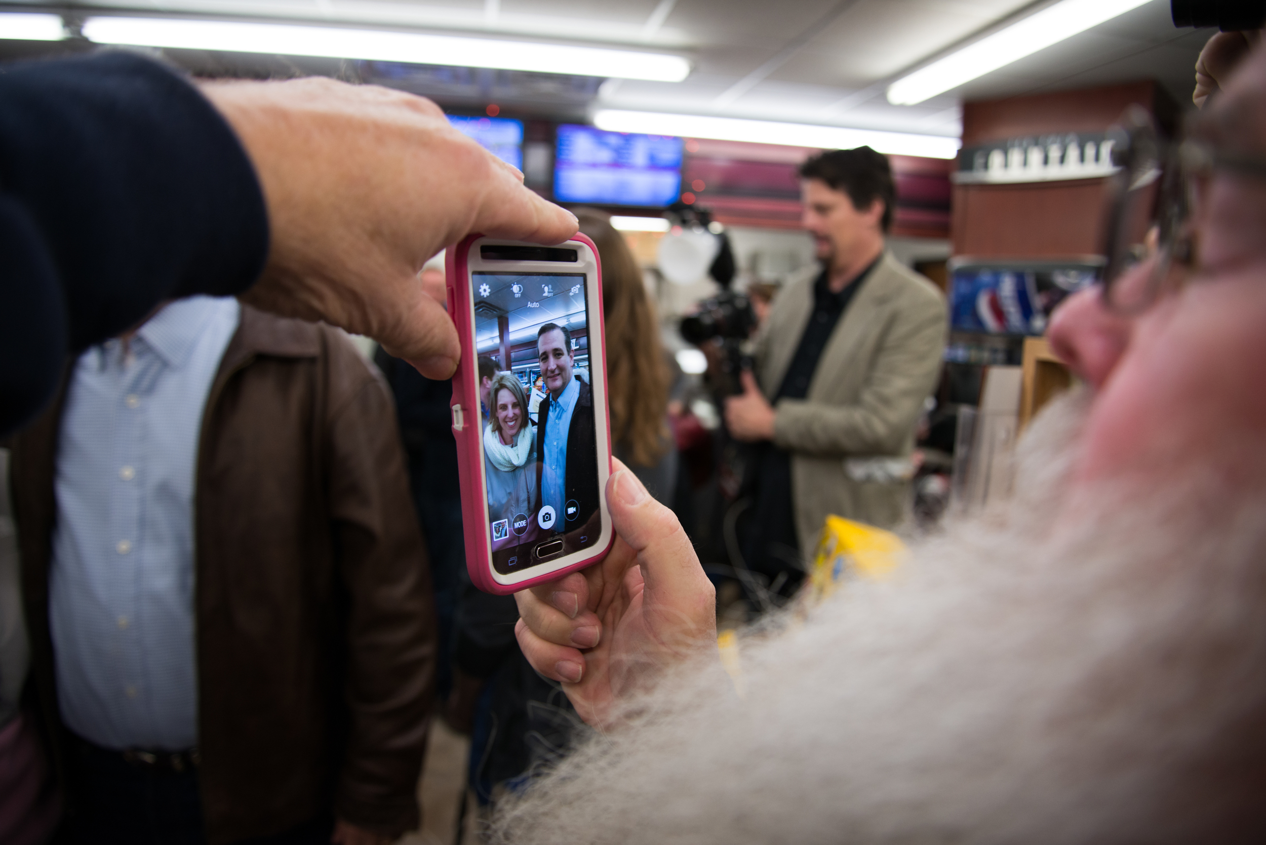  Republican presidential candidate Ted Cruz is seen through a cellphone screen as he poses for a photograph with a voter during a campaign stop at Casey’s General Store, in Tama, Iowa, on Nov. 29, 2015. 