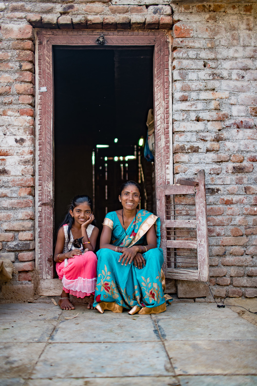 Mother and daughter at the doorway of their modest house.