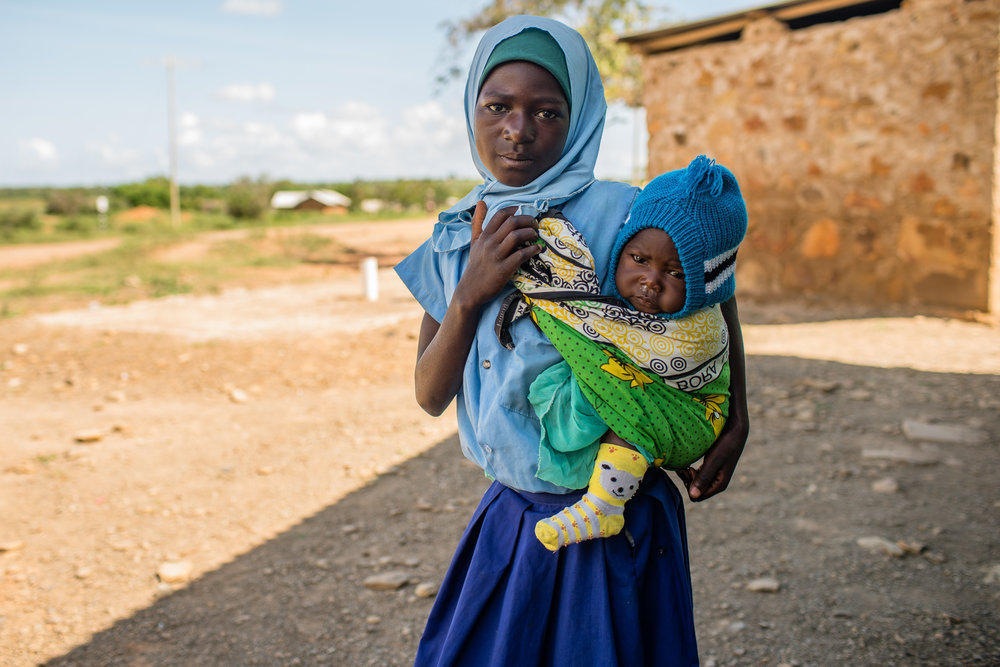 A young girl with her little brother waiting for her mother at a clinic outside Mombassa, Kenya.