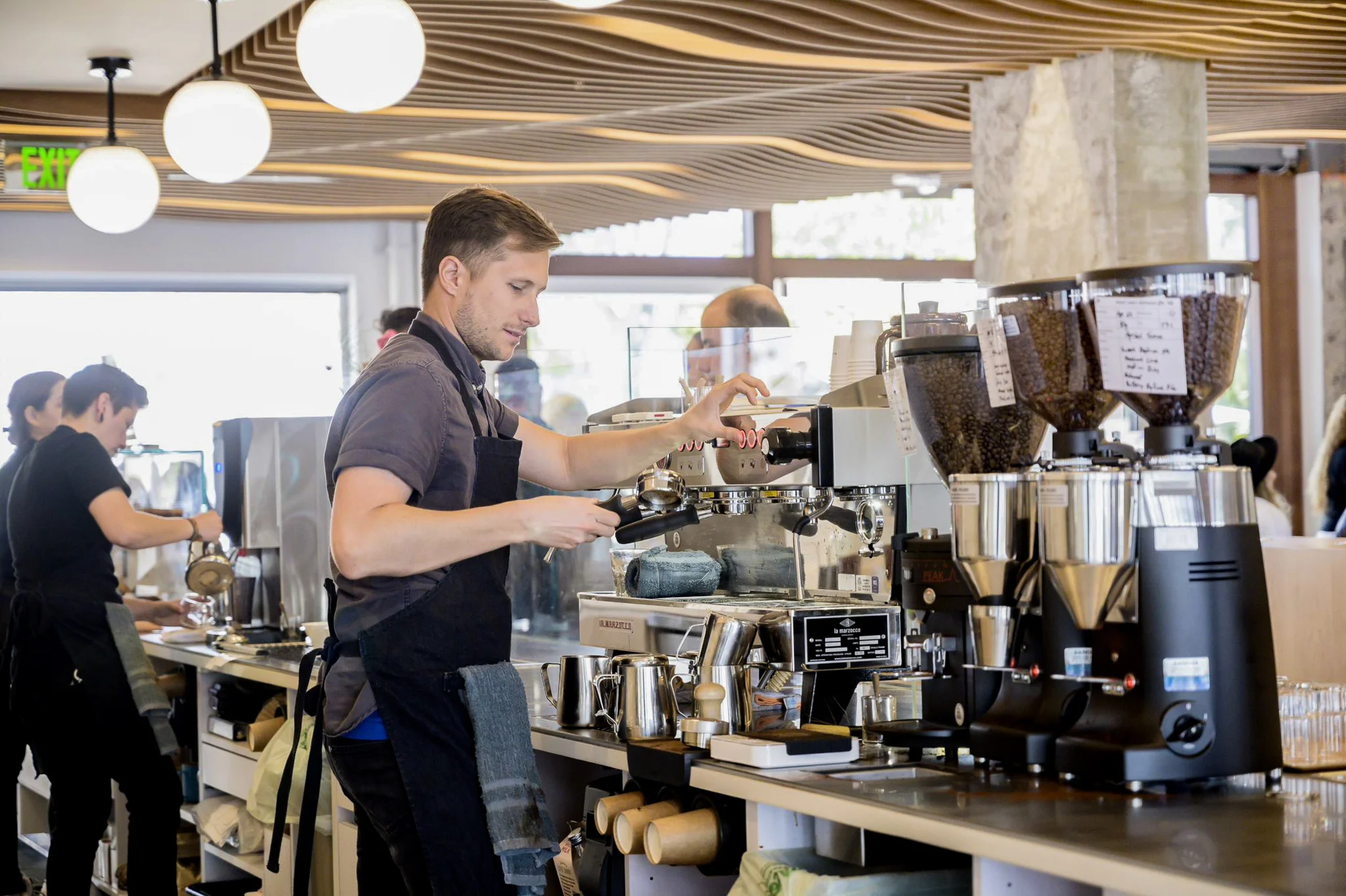 A barista operating an espresso machine in a bright, modern café