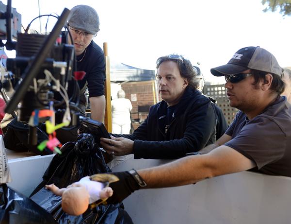 From left: director of photography Laffrey Witbrod, director Charles Dye and production designer Greg Eakins use a doll to set up a shot in a Dumpster for a movie being filmed Tuesday in the east alleyway, off Third Avenue, in downtown Longmont. (Lewis Geyer / Longmont Times-Call)