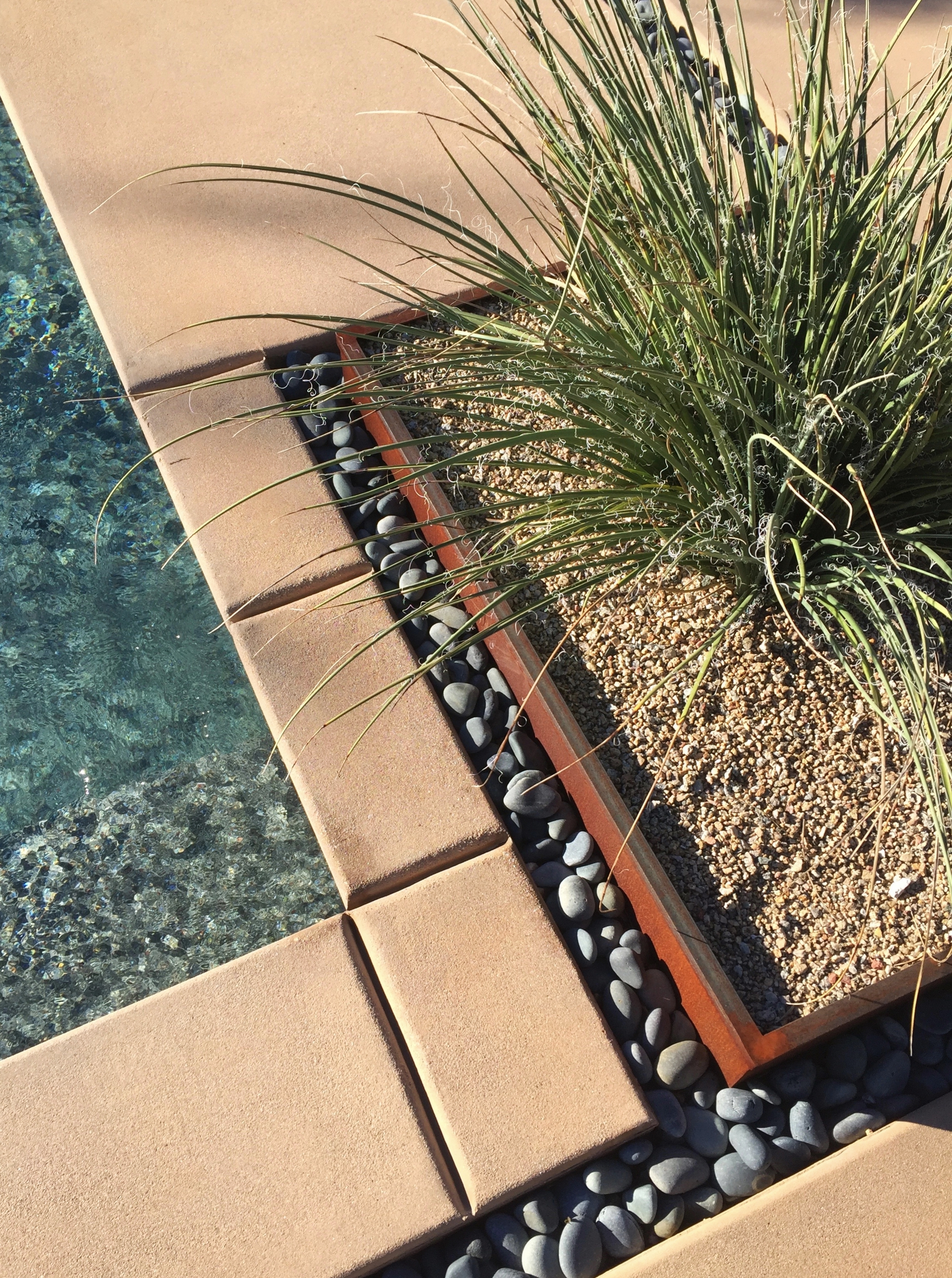 In-ground steel planter flanked by beach stone.
