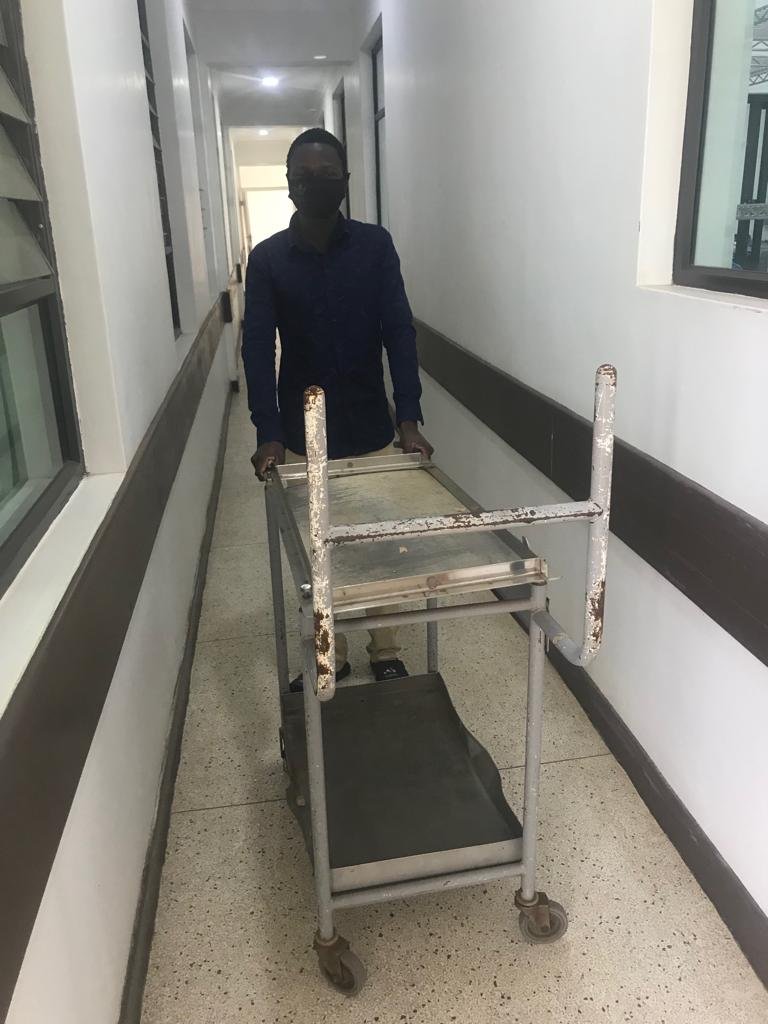  Volunteer Jonathan pushes a cart through the halls of a hospital. 