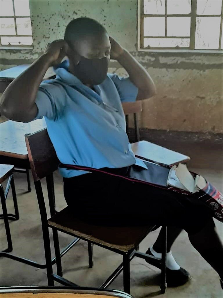  A recepient of partner WAM’s scholarship program at Kabudula Community Day Secondary School tries on a mask donated by Contine Investments, a local car hire company. 