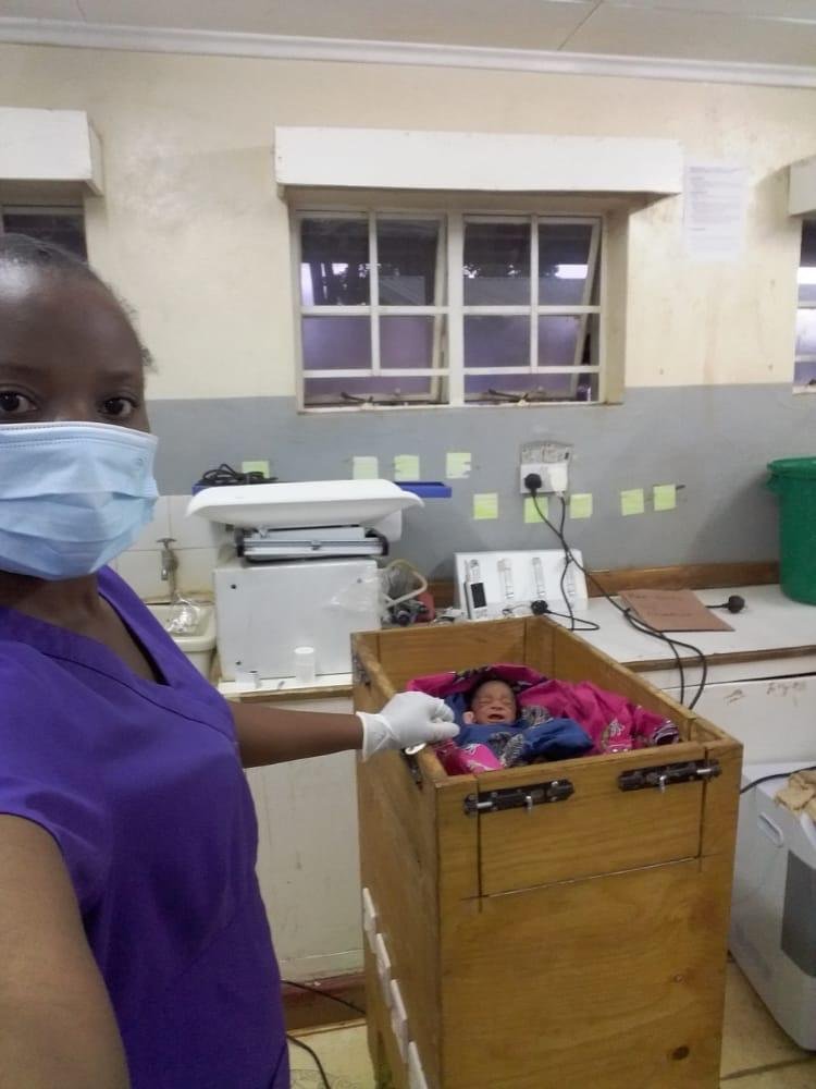  Funny Mataka, Community Midwife at Kab, stands next to the neonatal warmer made by local craftspeople from local materials, commissioned by AHA in 2019. 