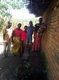 Mphatso and his family next to their home