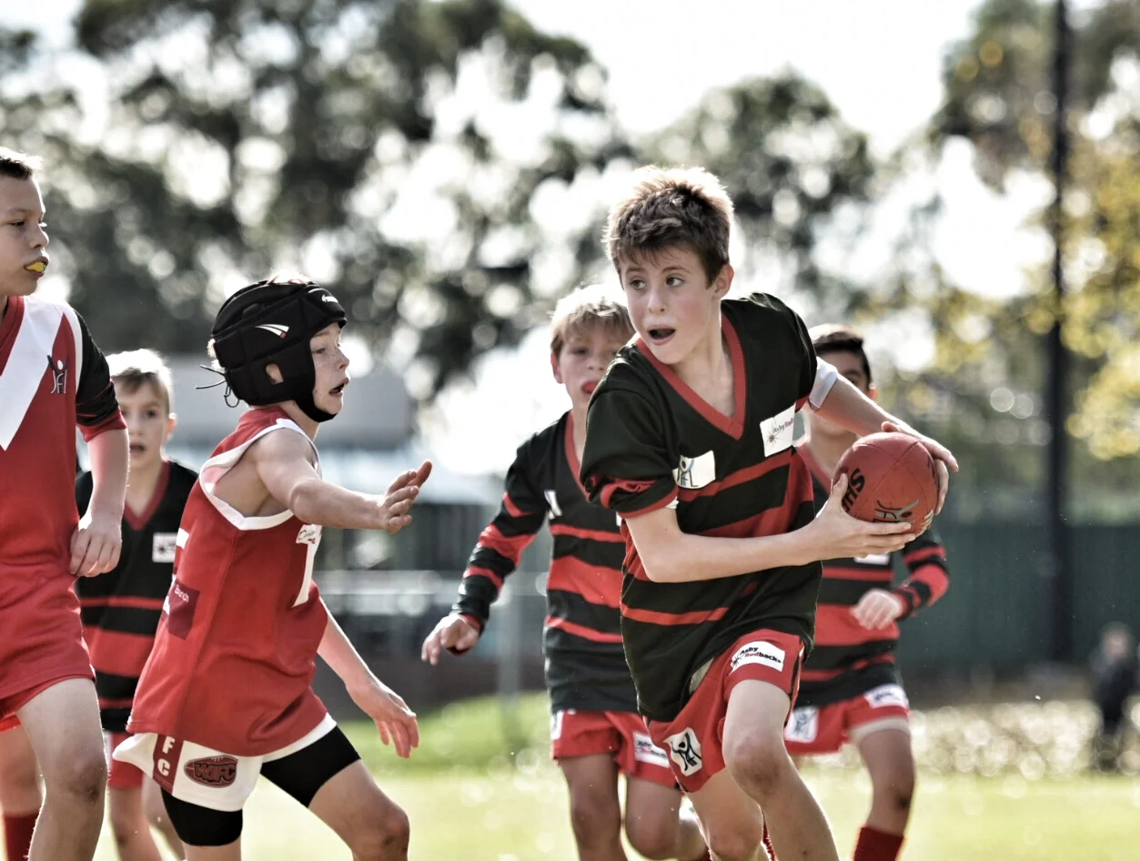 Logan Buckland busts out of the pack after a centre clearance by Auswide Communications U10 Red