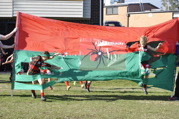 Taylor and Ollie from Frenchams U11 Red burst through their 50 Game Banner
