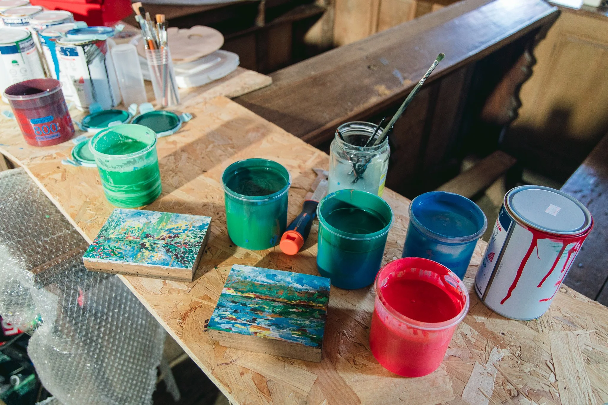 Miroir Normand, Daniel Nicolaevsky, église Saint-Vincent de Martagny, 2026 : pots de peinture et petits tableaux sur la table de travail.