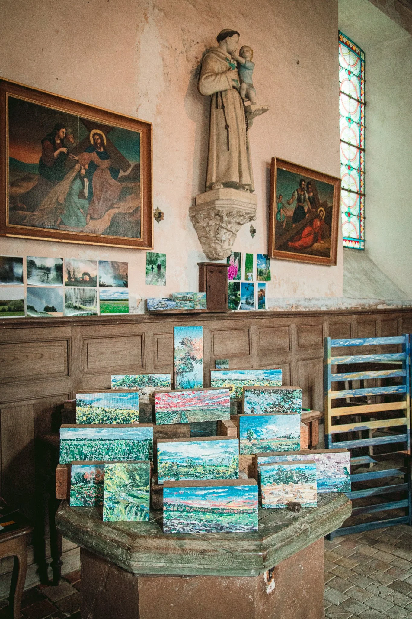 Miroir Normand, Daniel Nicolaevsky, église Saint-Vincent de Martagny, 2026 : douves peintes empilées sous une statue et des tableaux.