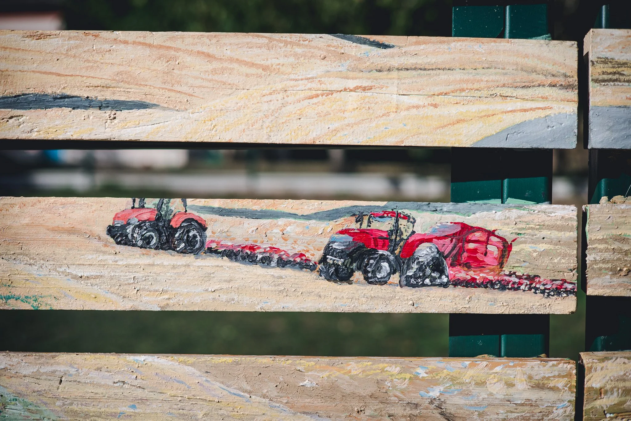 Autocollant peint d'une voiture rouge sur une planche en bois face à un fond flou de nature