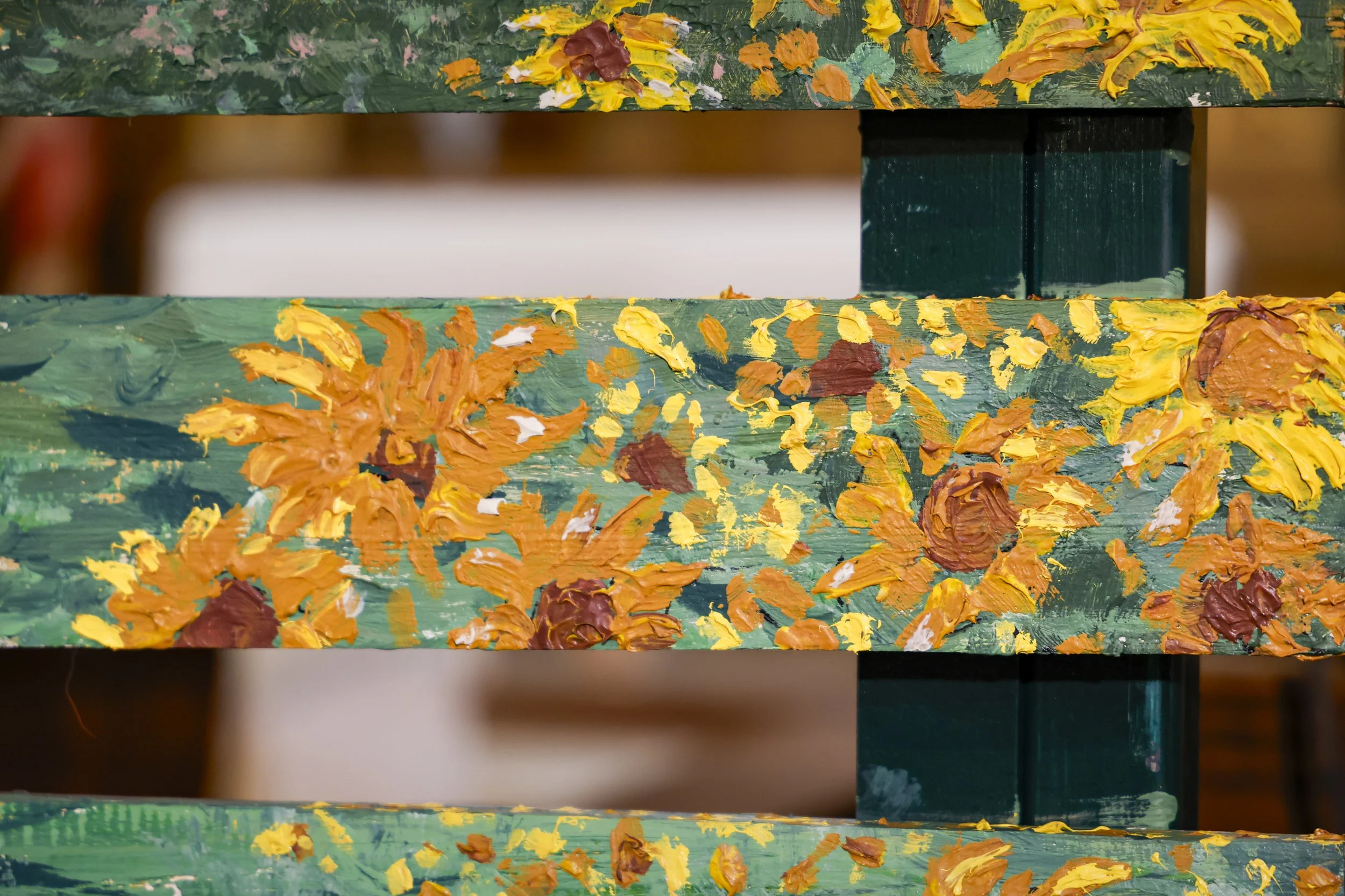 Une peinture à laquelle on peut voir des coups de pinceau de différentes couleurs comme le jaune, l'orange, le marron, le blanc et le vert, sur une surface en bois.