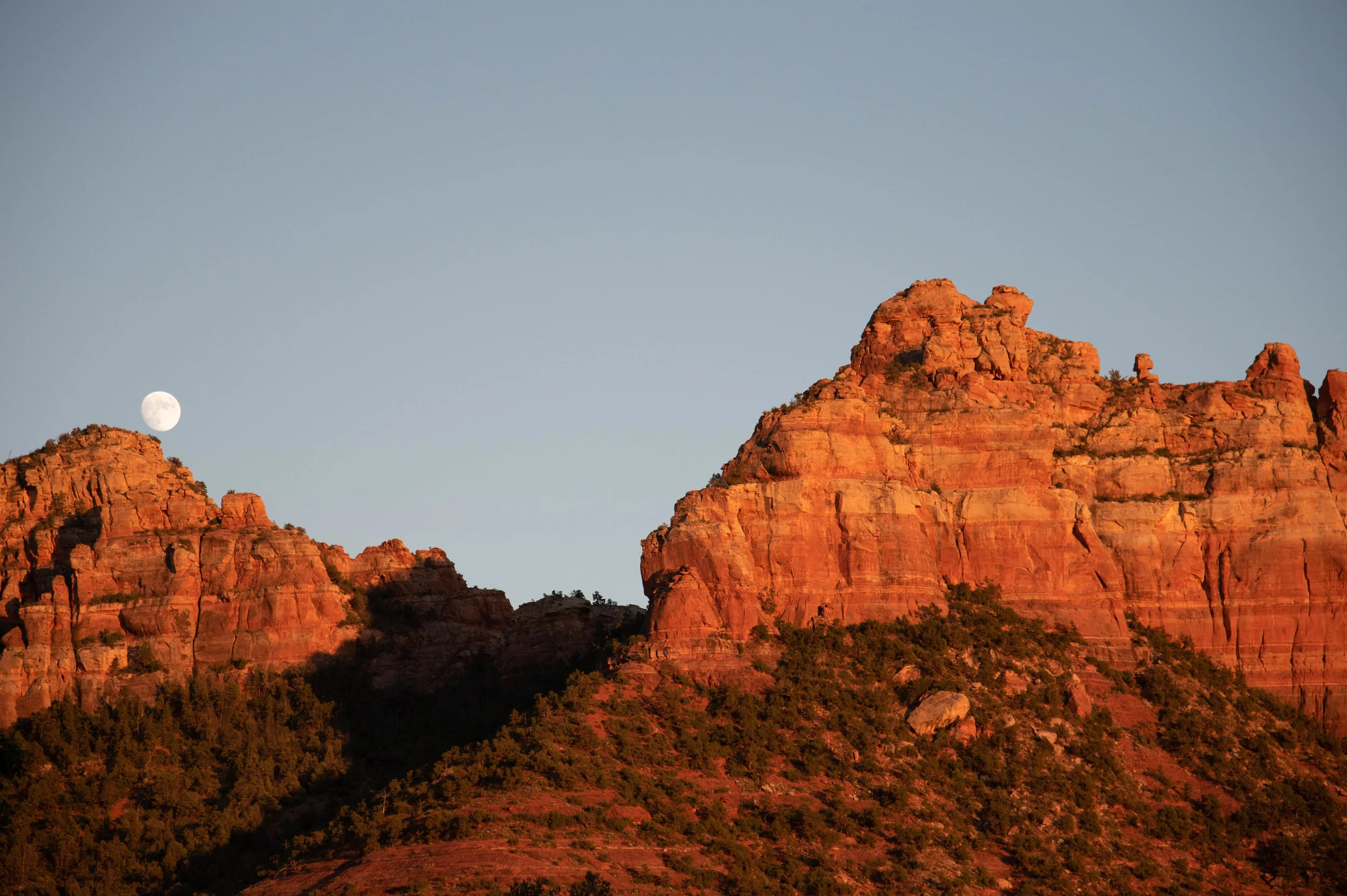 Moon rising at sunset over red rocks