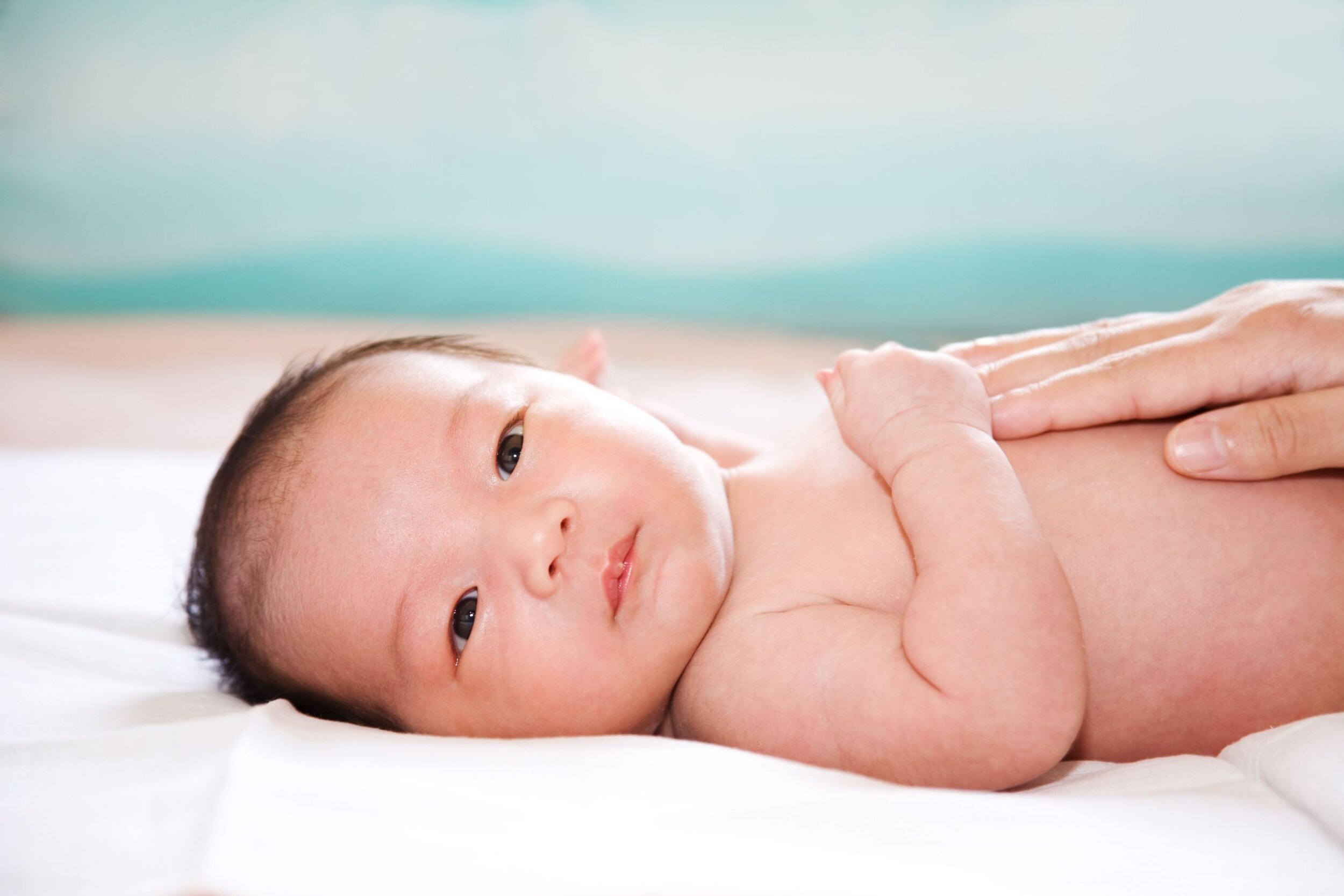 newborn baby with parent's hands on cloth