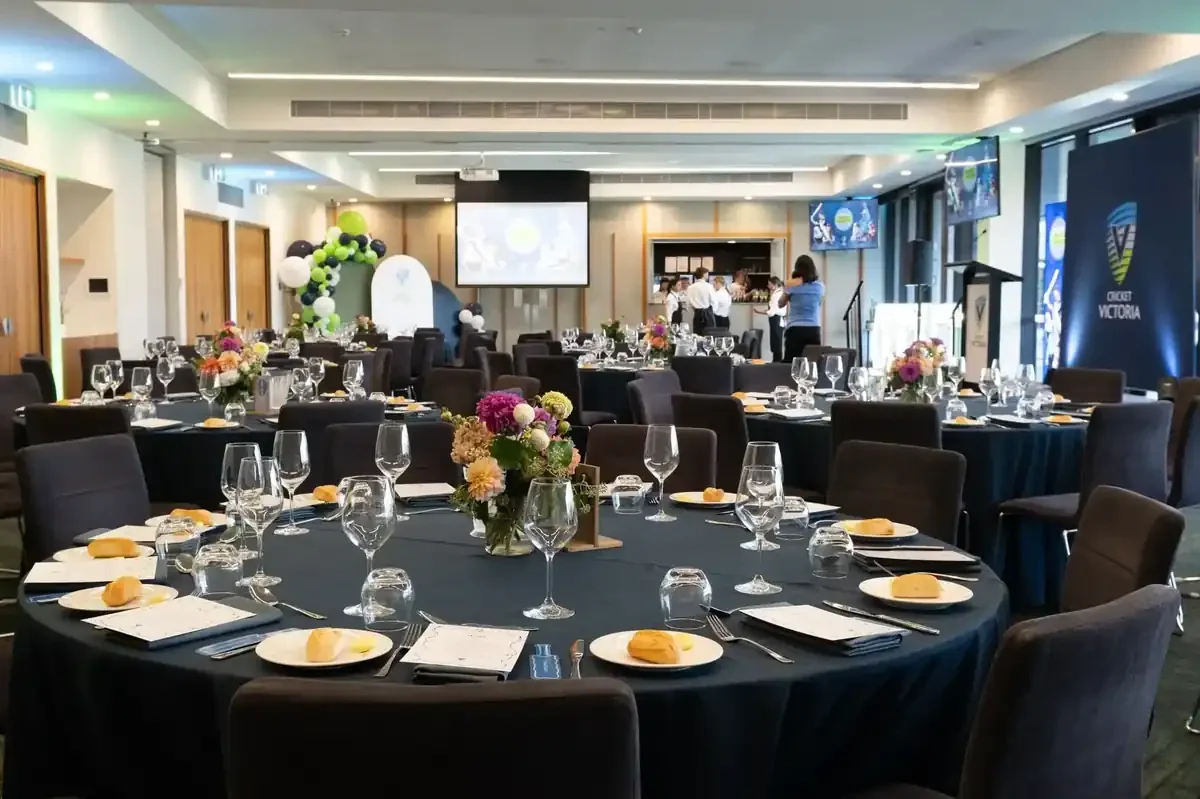 A banquet hall set up for an event features round tables with dark blue tablecloths