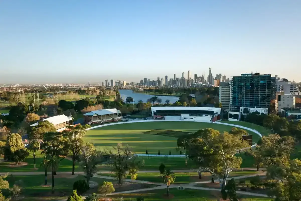An aerial view of a green sports oval surrounded by trees and parklands