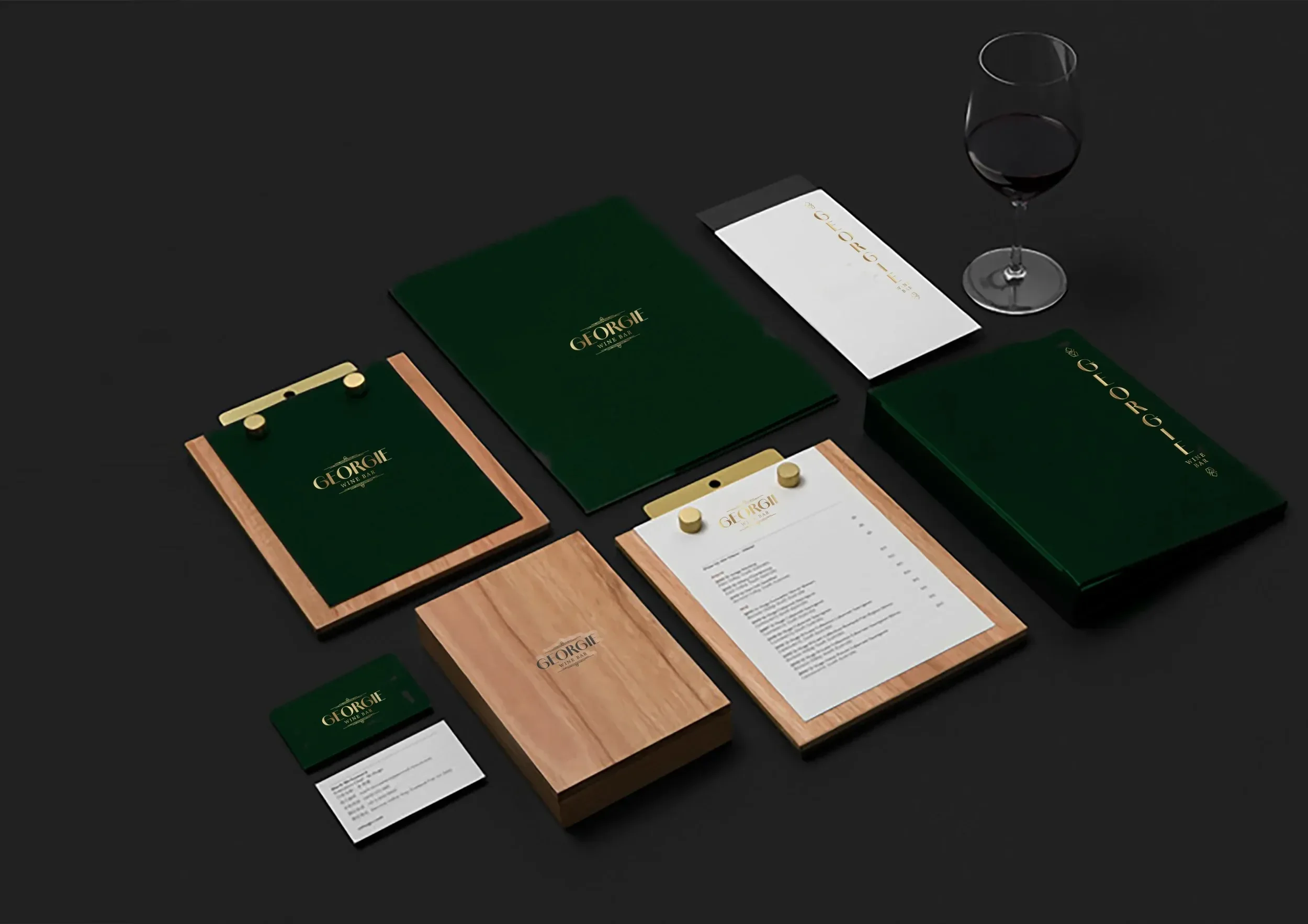 Set of branding materials for George Wine Bar, including menus, business cards, wooden and green folders, and a glass of red wine on a black surface.