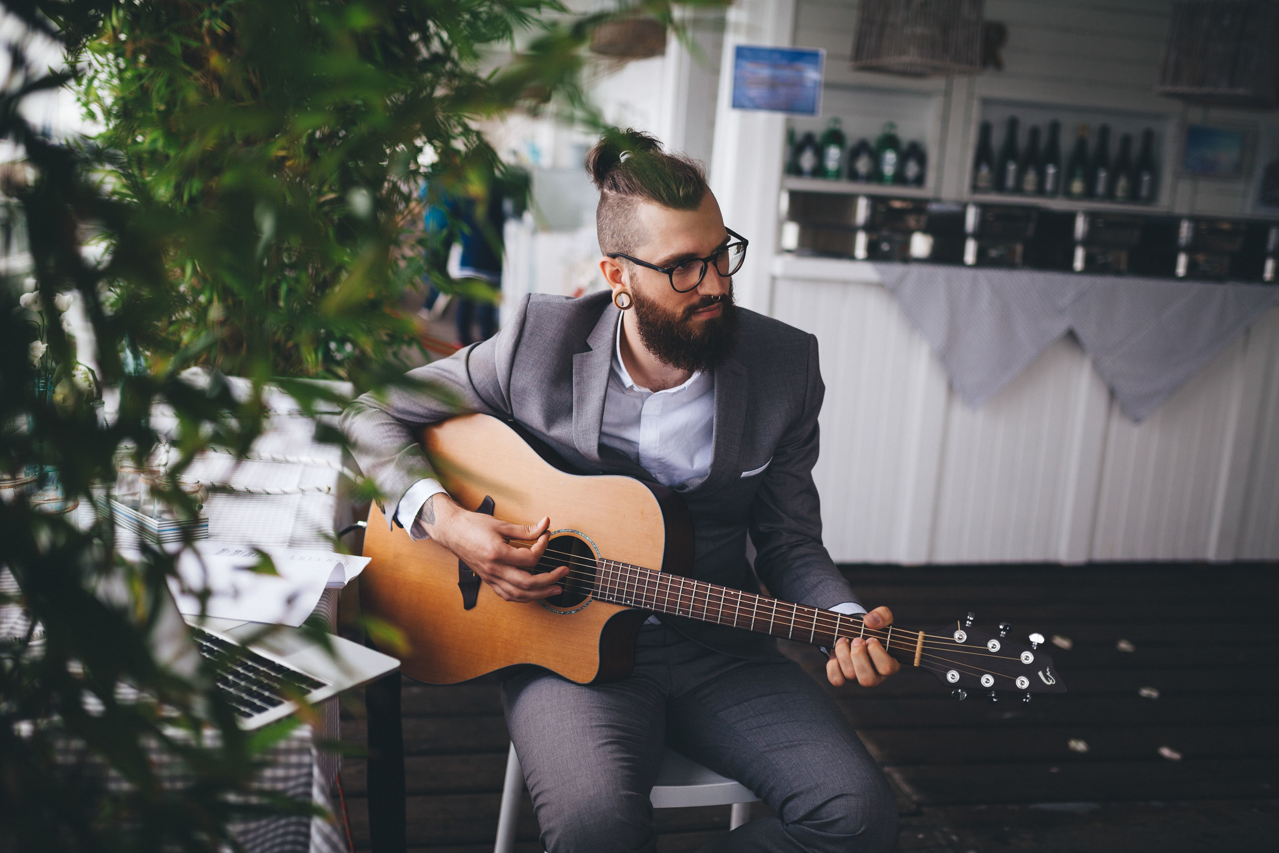 Bärtiger Gitarrist mit Brille spielt bei einer Hochzeit in der Seebar Kiel Gitarre. Das Foto ist bei einer Hochzeit in Kiel von Phil Schreyer entstanden.