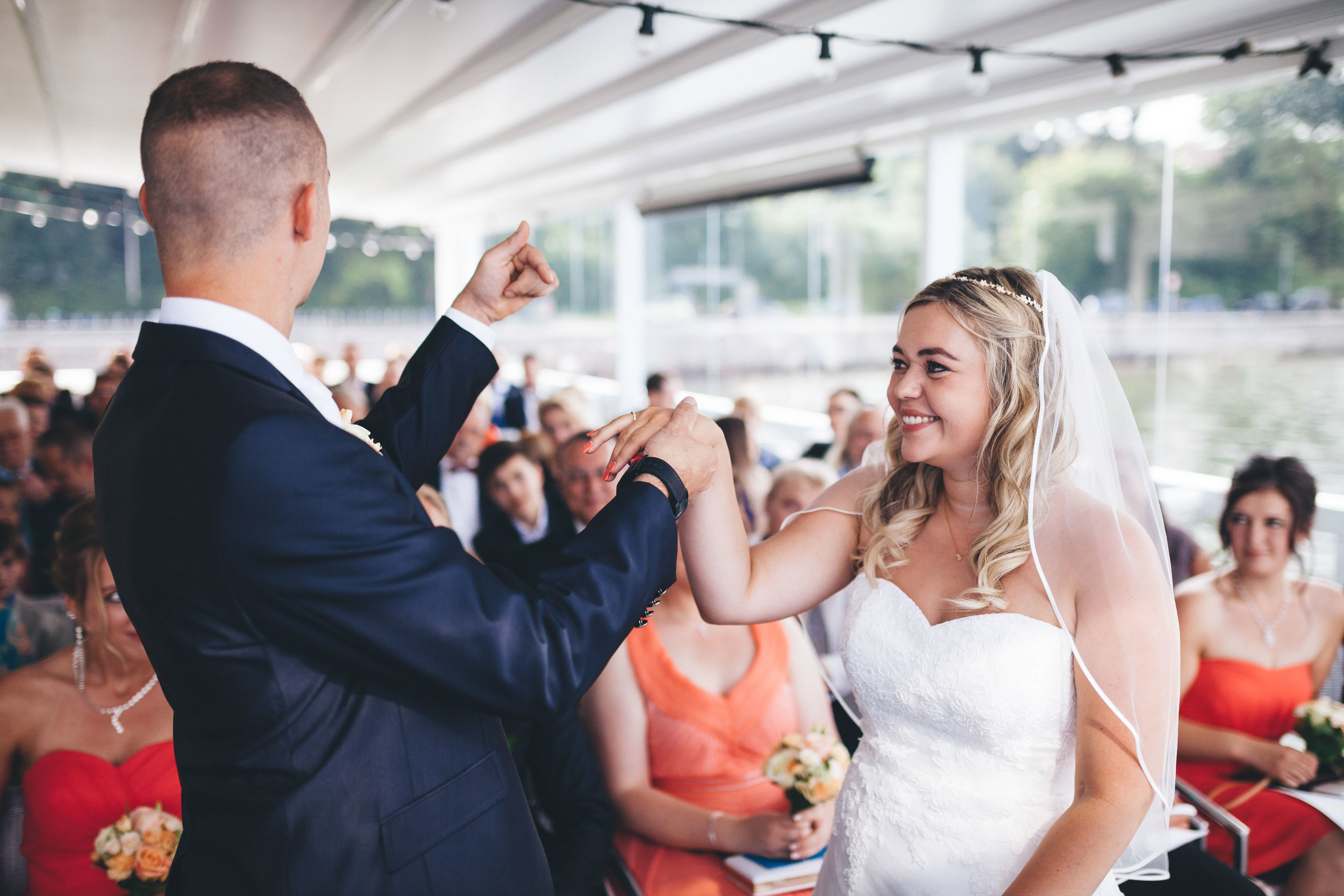 Ein stolzer Bräutigam hebt die hand seiner Braut in die Höhe und freut sich über die frische Verlobung. Fotografier in einer Hochzeitslocation in Kiel von Fotograf Phil Schreyer