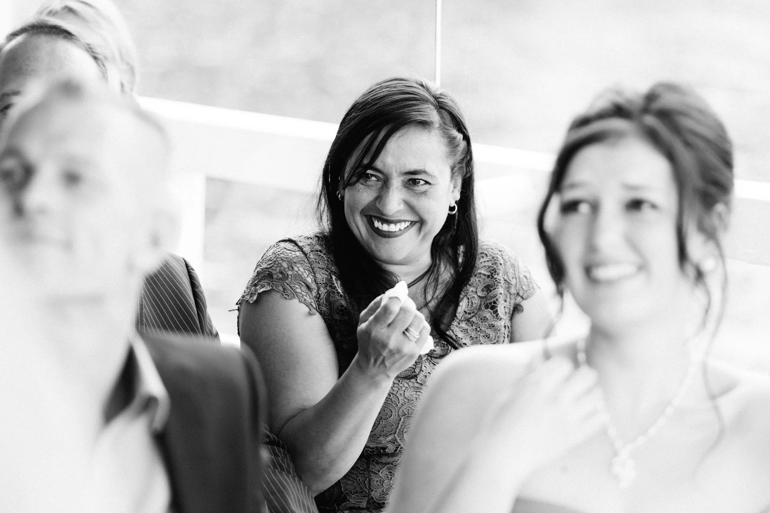 Eine Frau lacht mit Tränen in den Augen auf einer Hochzeit in Kiel an der Förde. Die Aufnahme ist in Schwarz Weiß und von Hochzeitsfotograf Phil Schreyer geschossen.