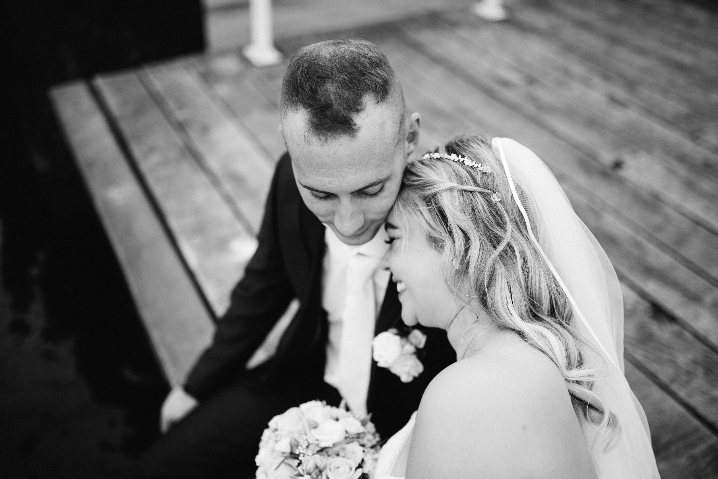 Eine Portraitaufnahme von einem Hochzeitspaar in Schwarz Weiß. Sie lehnt sich an seine Schulter und beide sind in ihrer eigenen Welt versunken. Die Aufnahme ist bei einer Hochzeit in Kiel entstanden. 