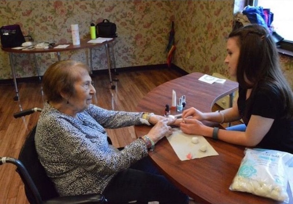 Ellen giving a senior a manicure at a GlamourGals makeover.