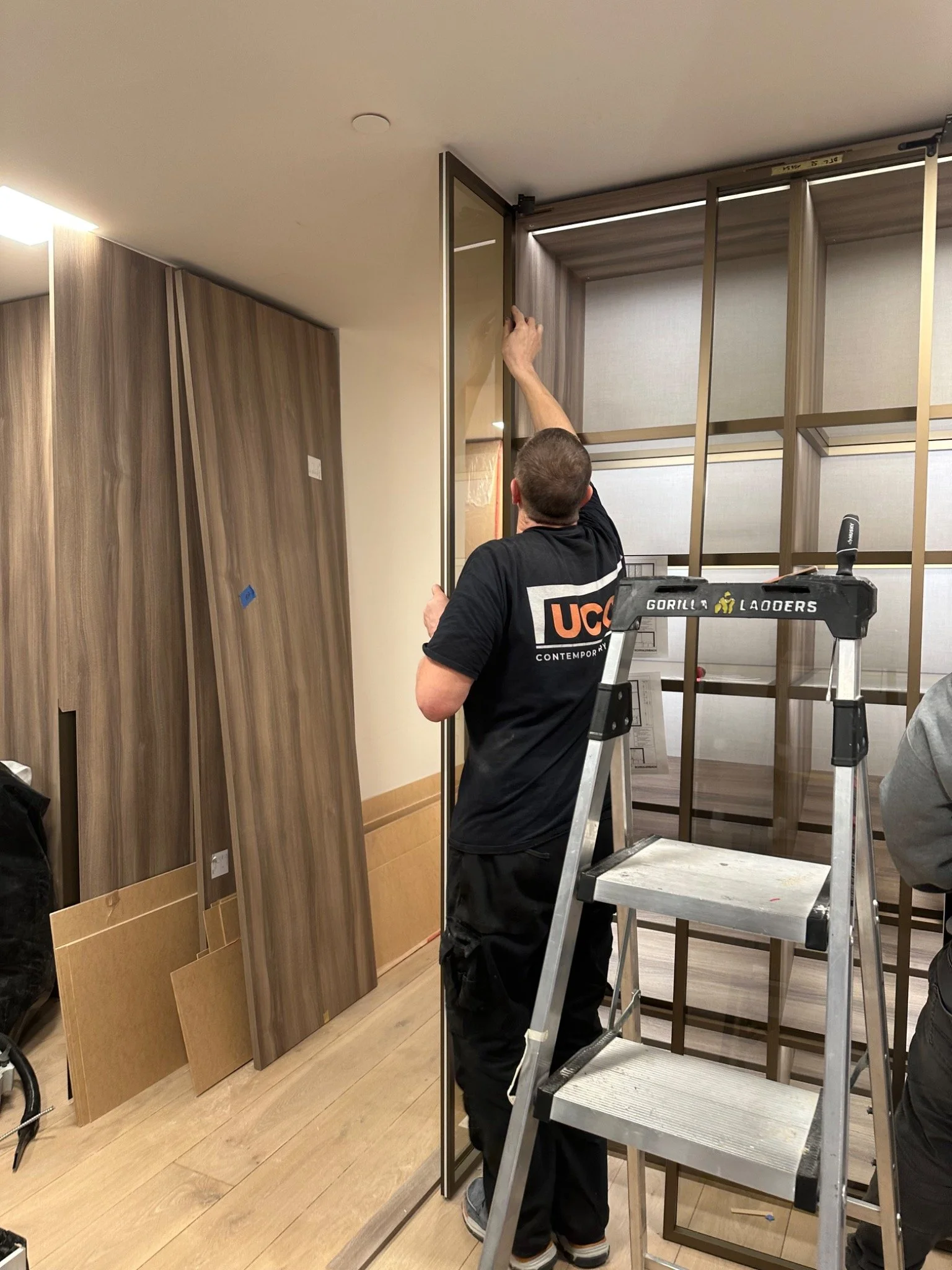 UCON installer adjusting a glass closet door during custom closet installation and field alignment.