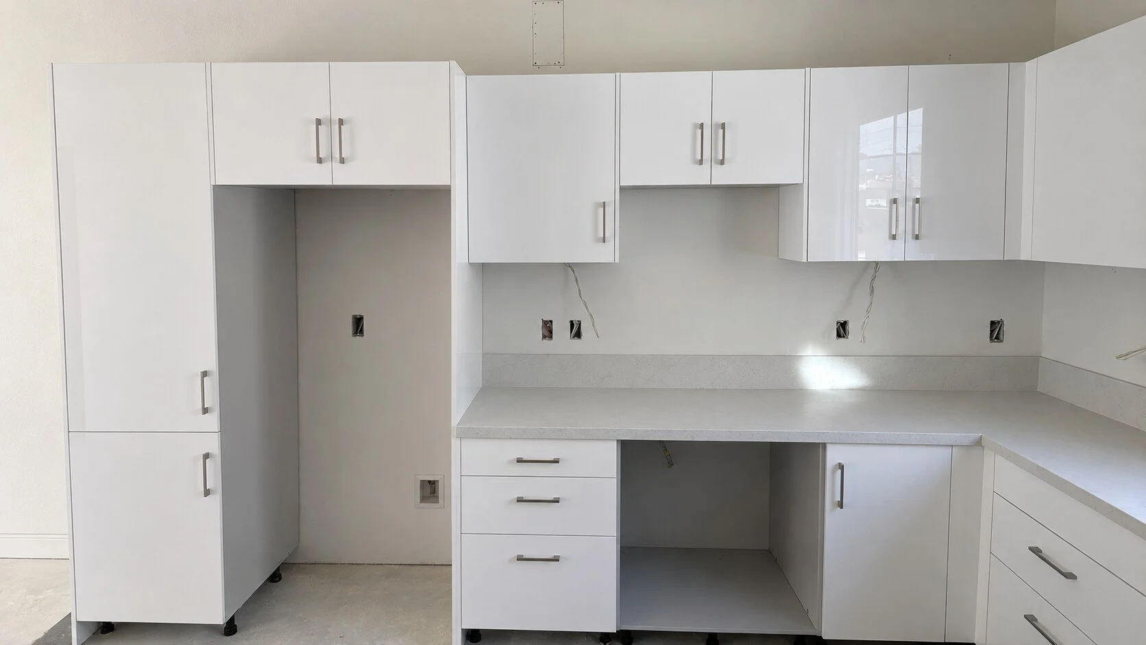 Late-stage kitchen installation at the Cantera development before toe-kick completion and final appliance integration