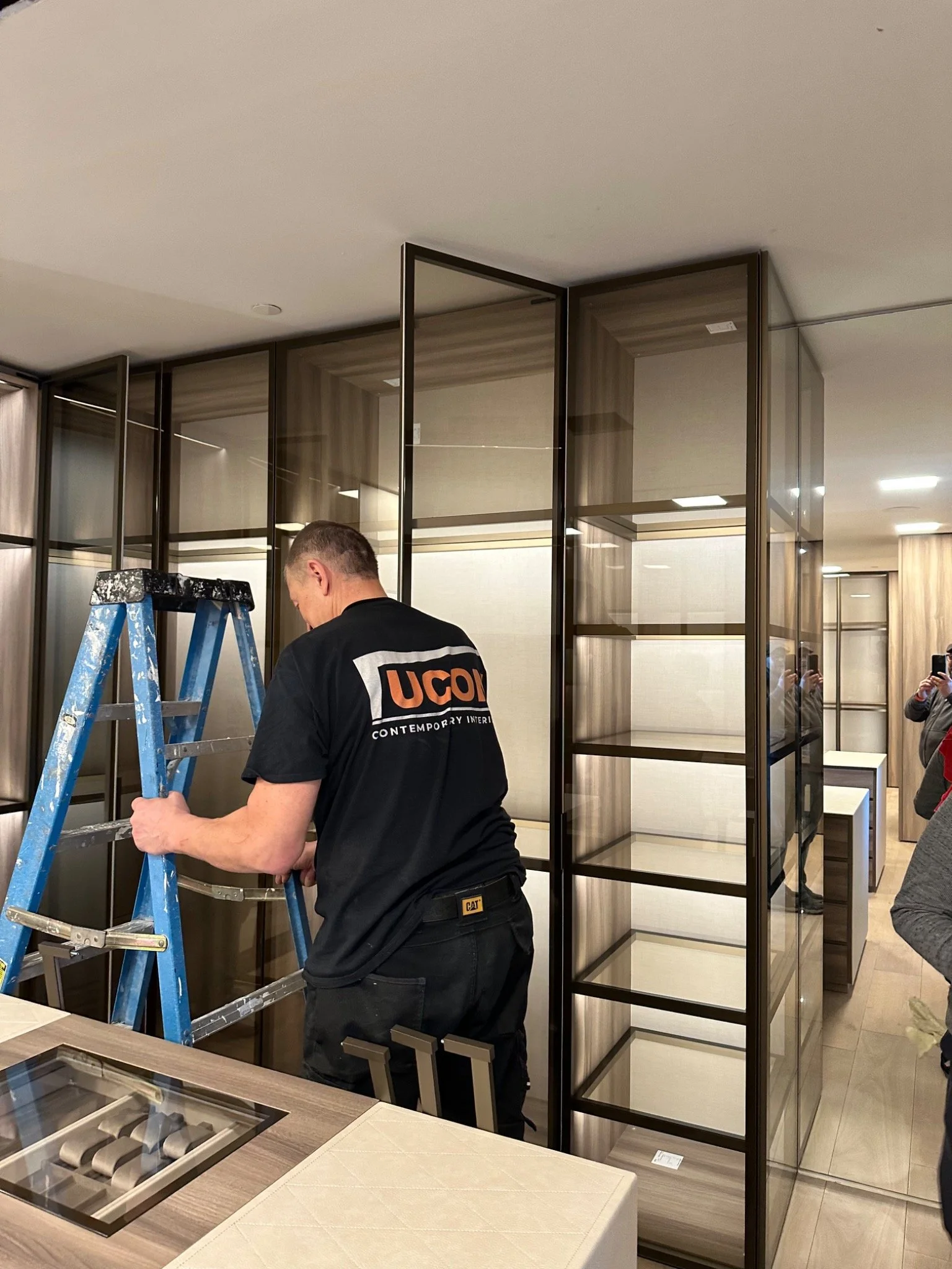 UCON installer working on glass door alignment during custom closet and storage system installation.