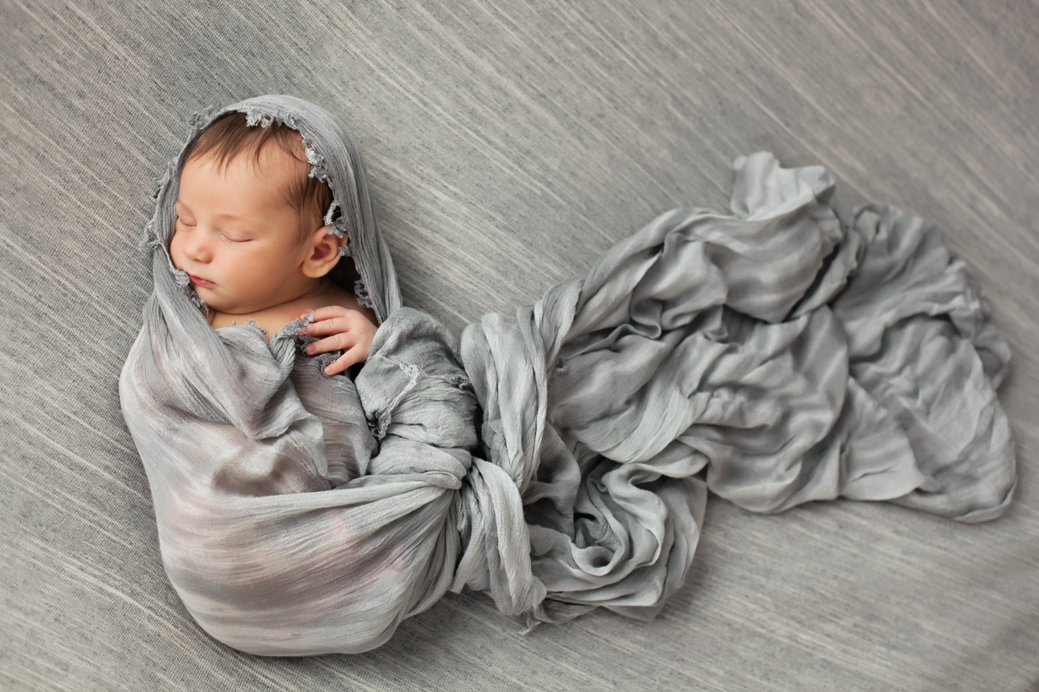 baby in a grey wrap sleeping peacefully