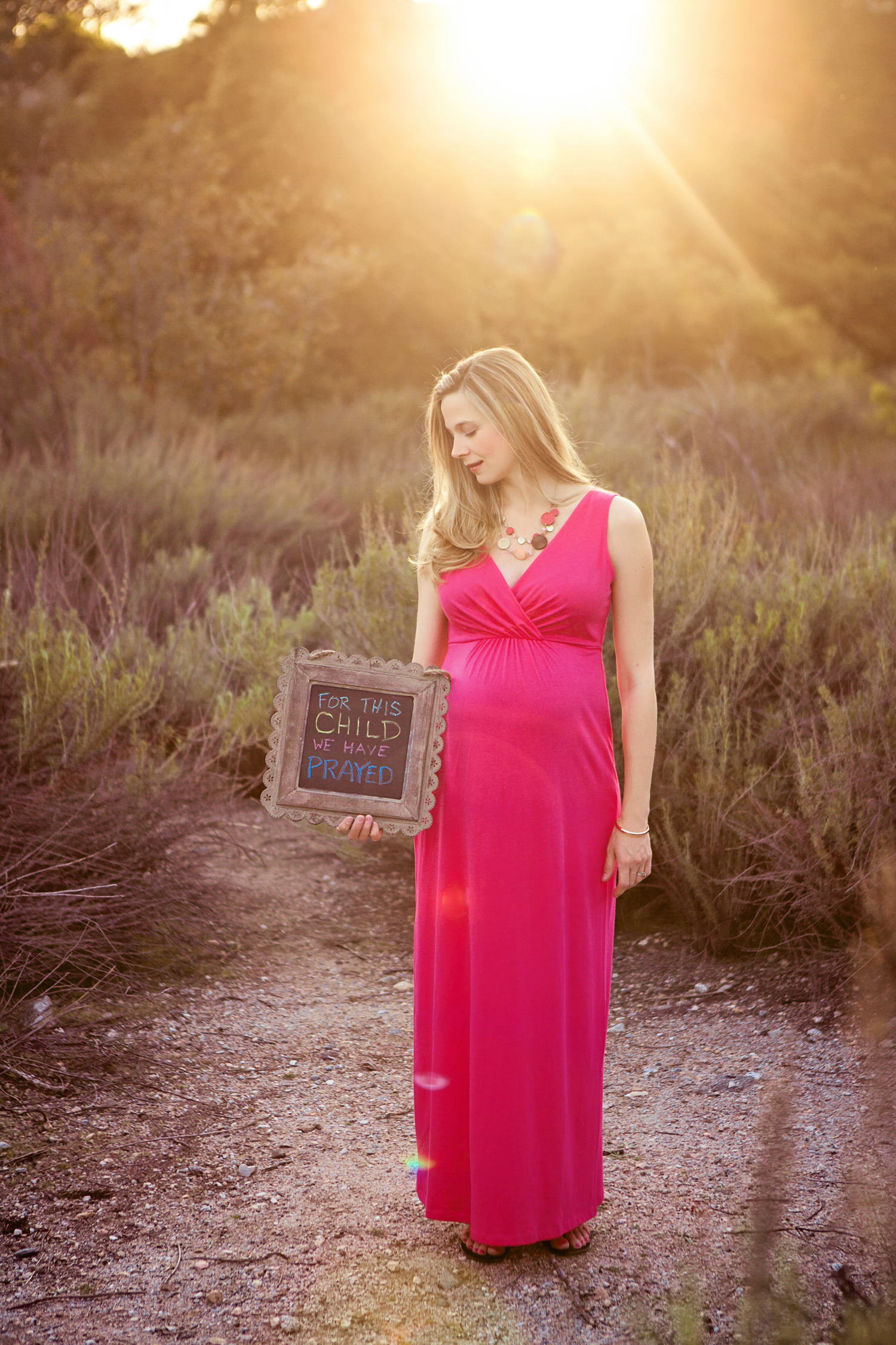 pregnant woman in hot pink dress holding sign