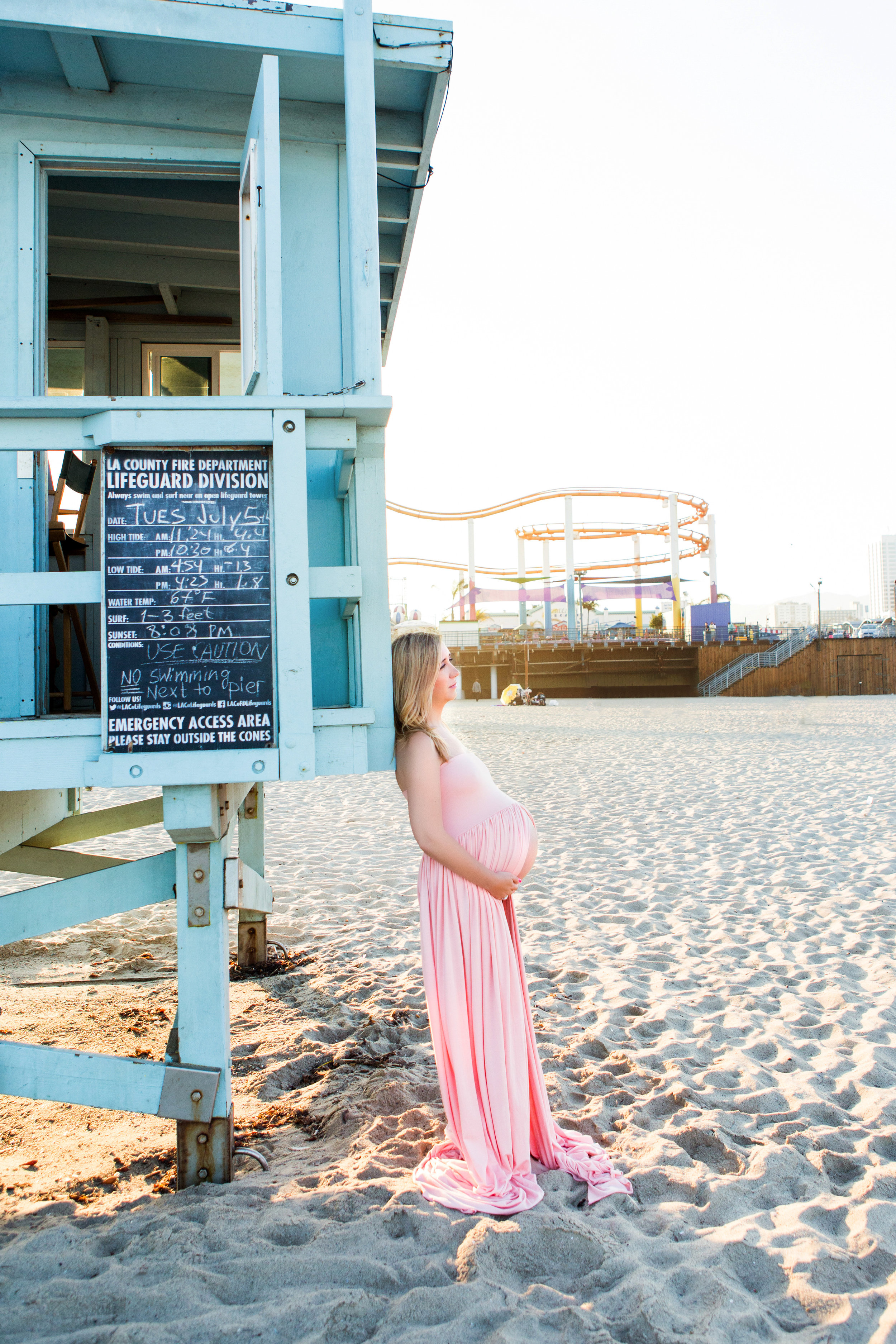 expecting lady leans against lifeguard stand at santa monica pier