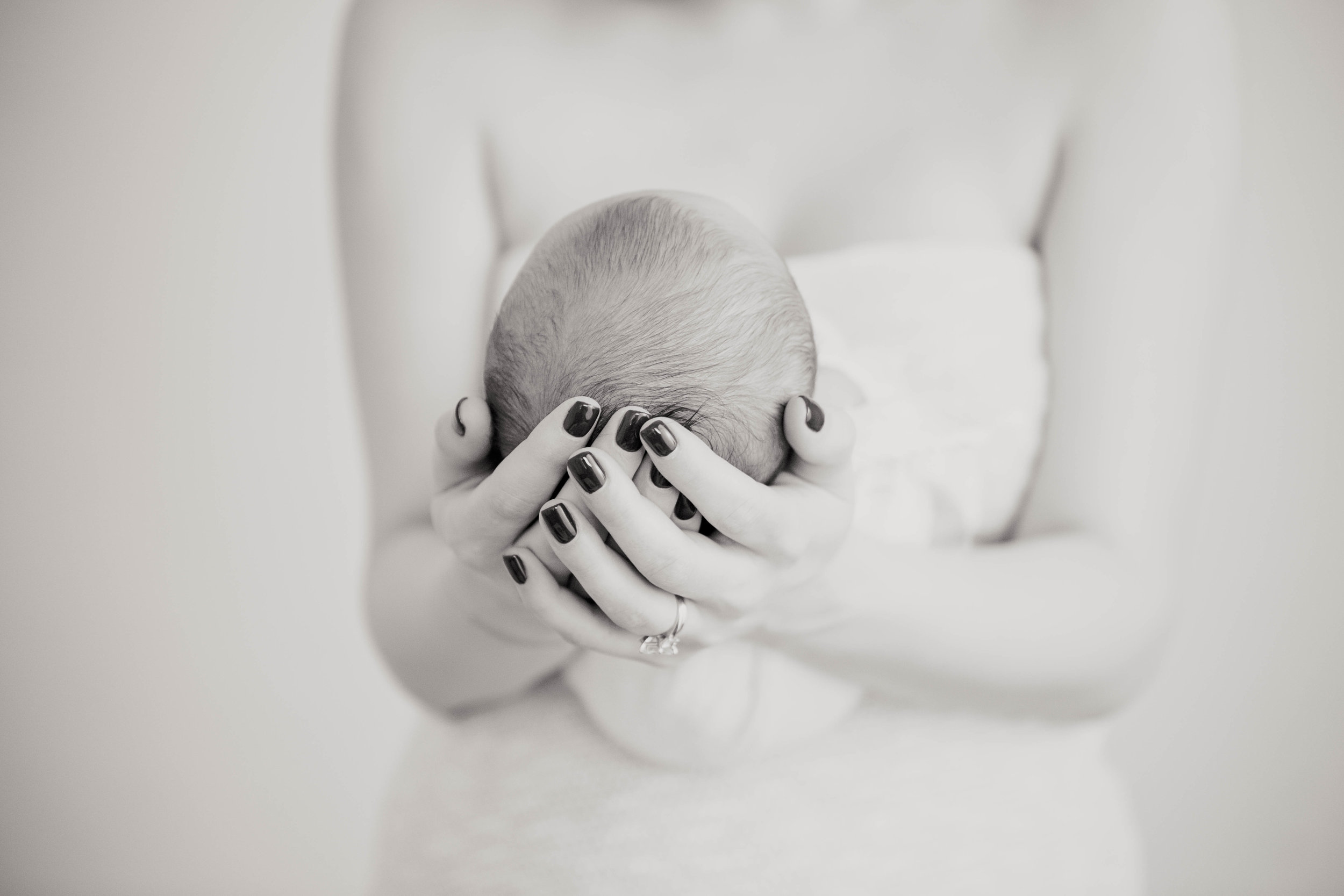 new mom with a ring and manicured nails holding her newborn lovingly