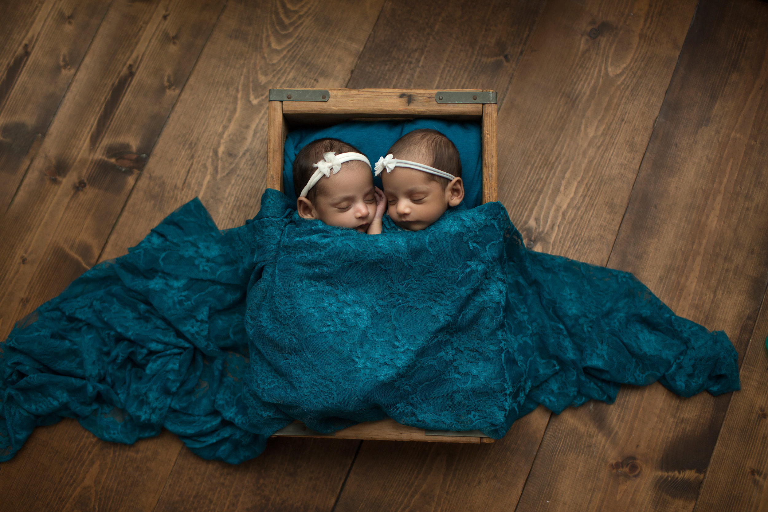 twin girls snuggling under vivid blue blanket