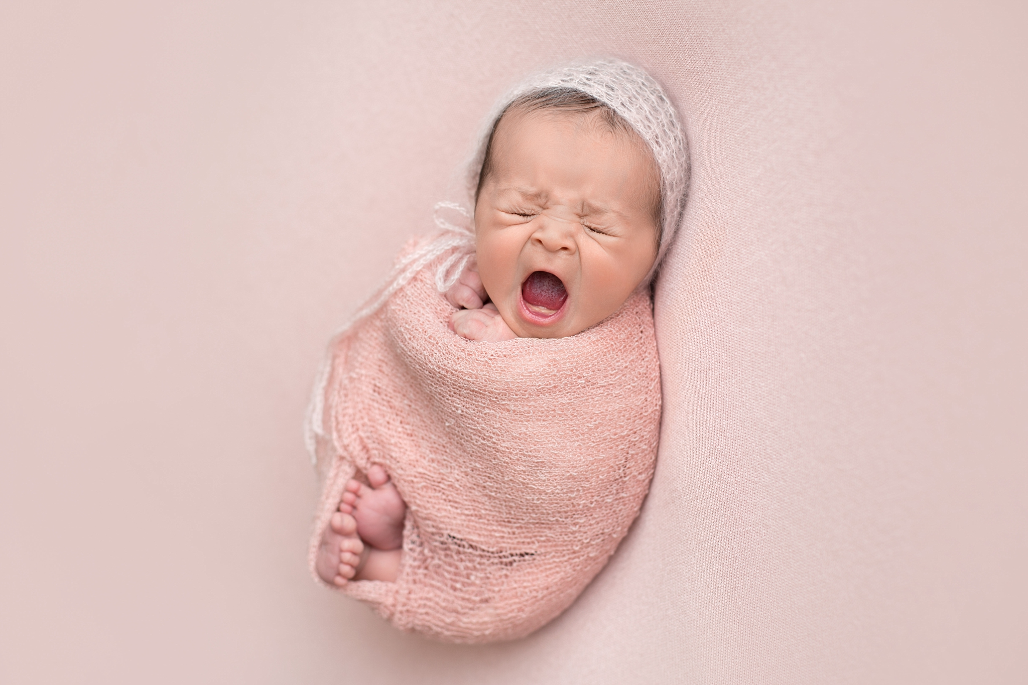baby girl yawning wrapped in pink