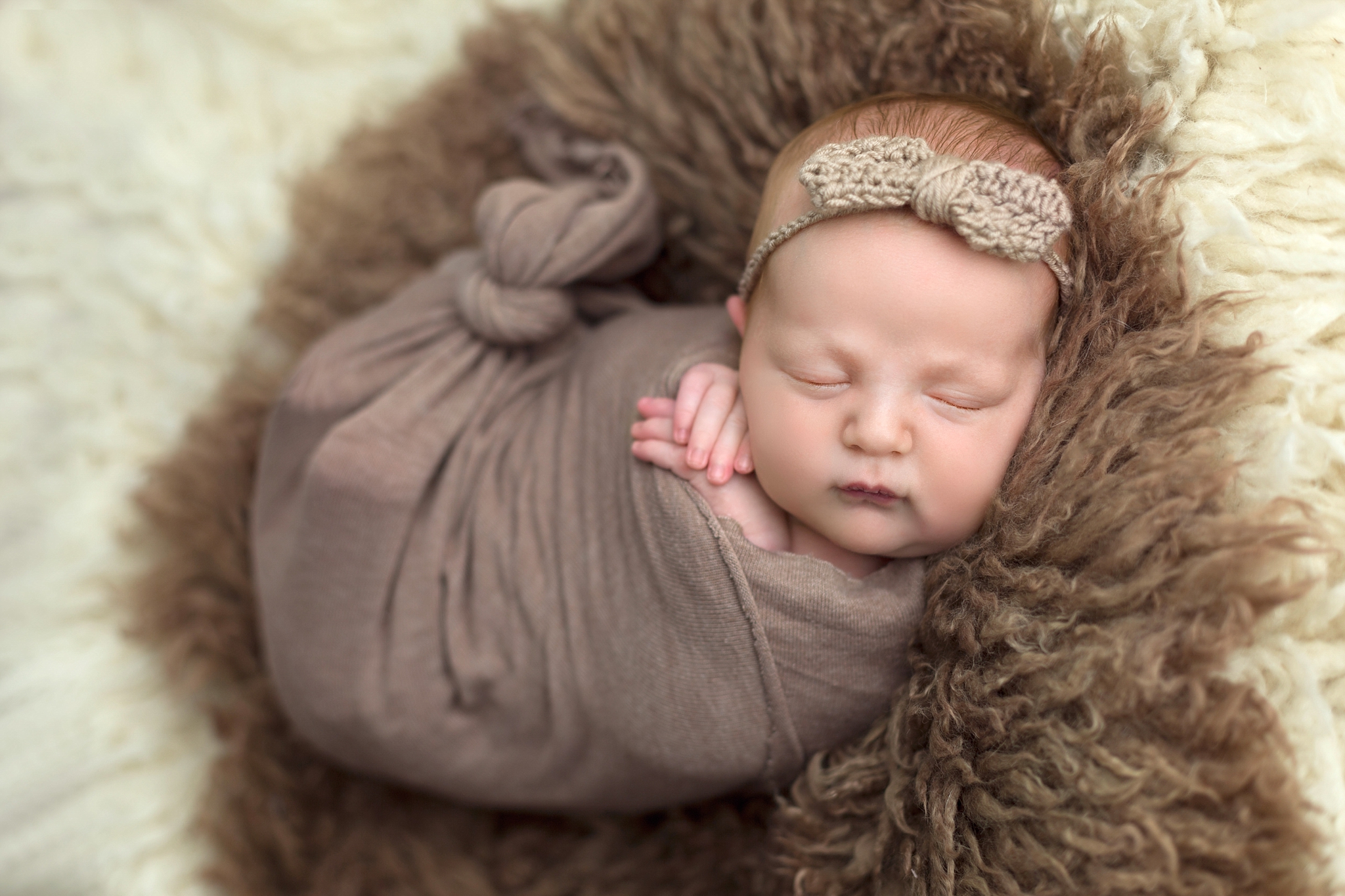 baby napping on brown rug with bow