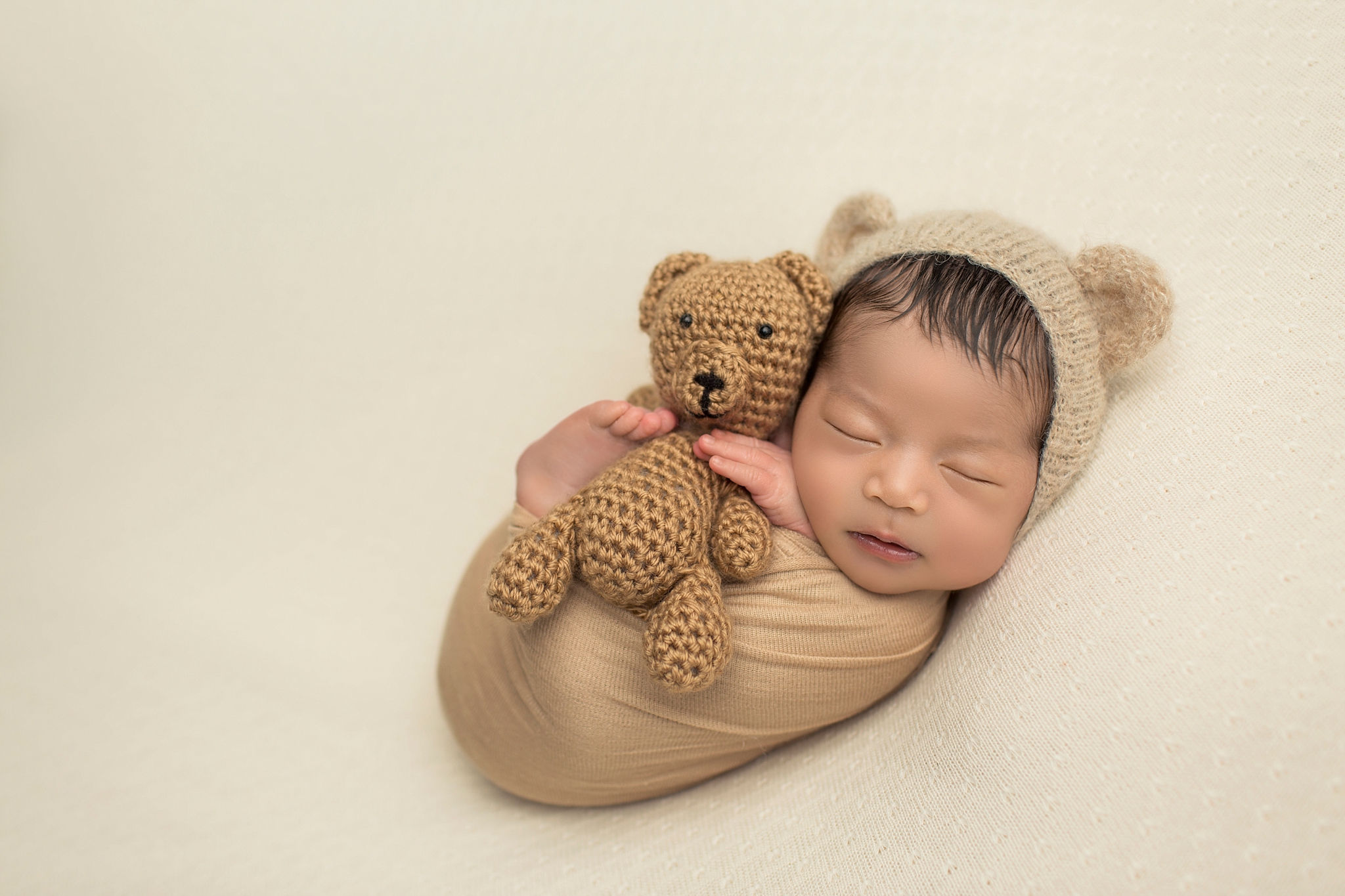 baby holding a tiny teddy bear
