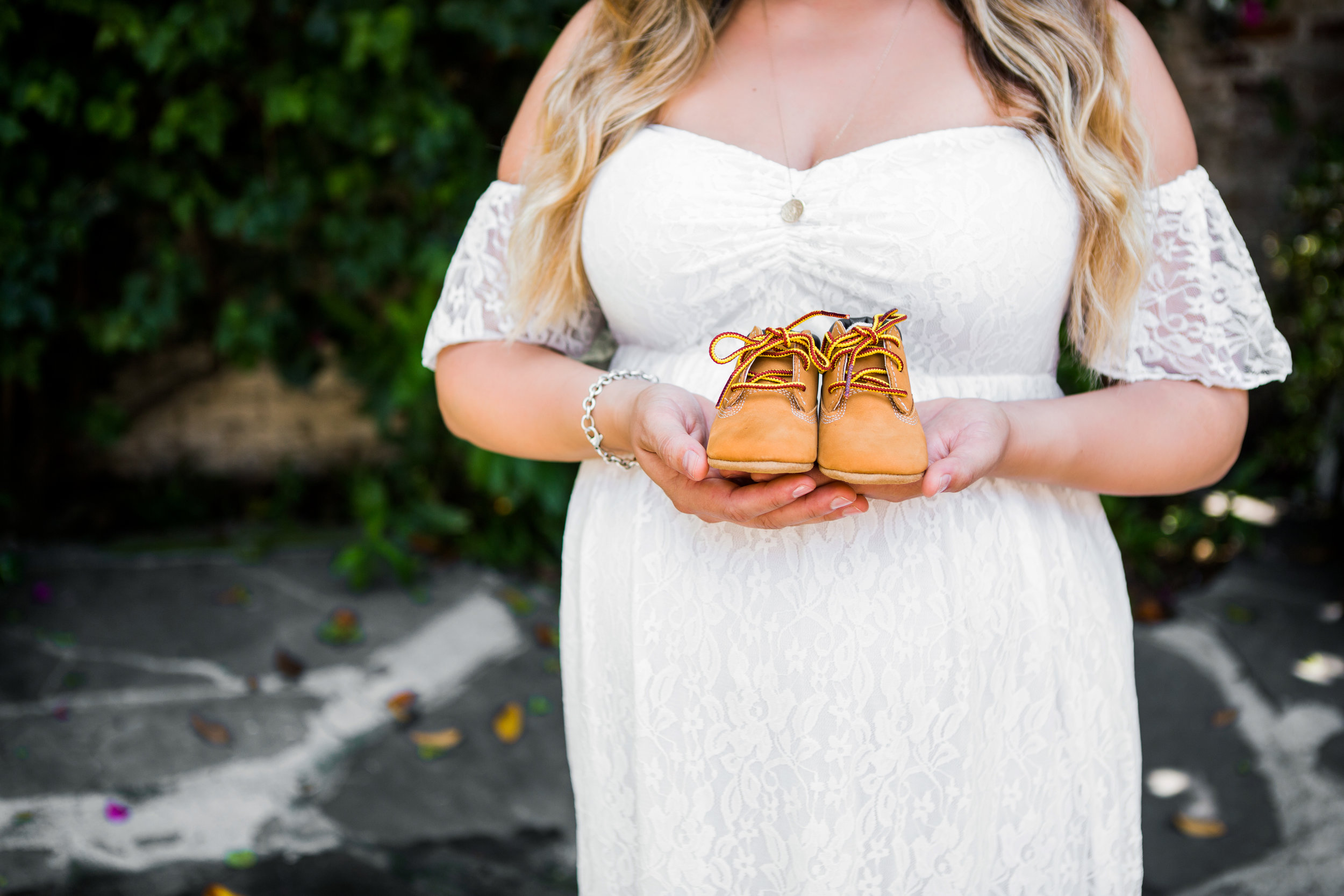 expecting mom holding newborn booties next to her belly