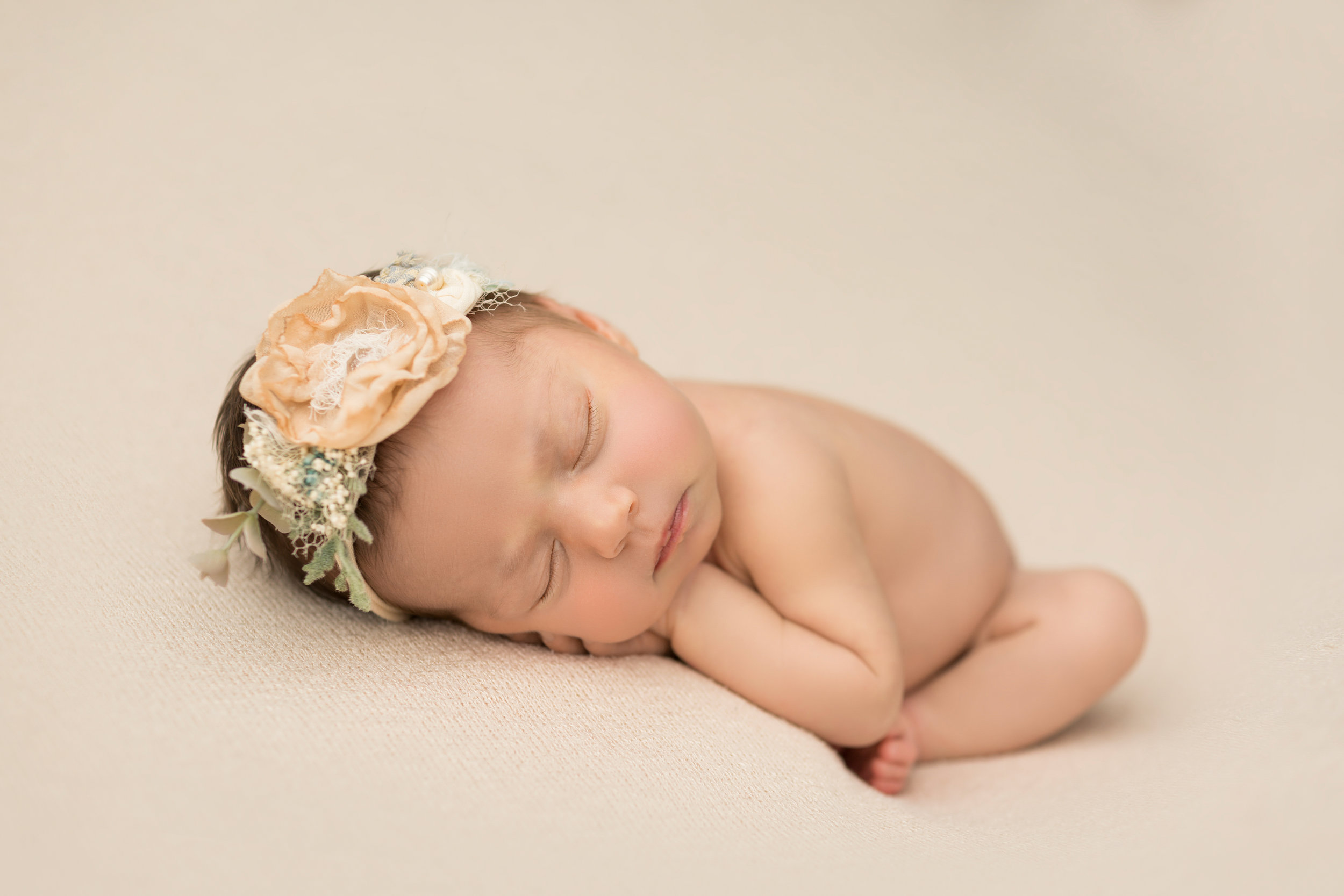baby wearing headband with big pink flower resting her head