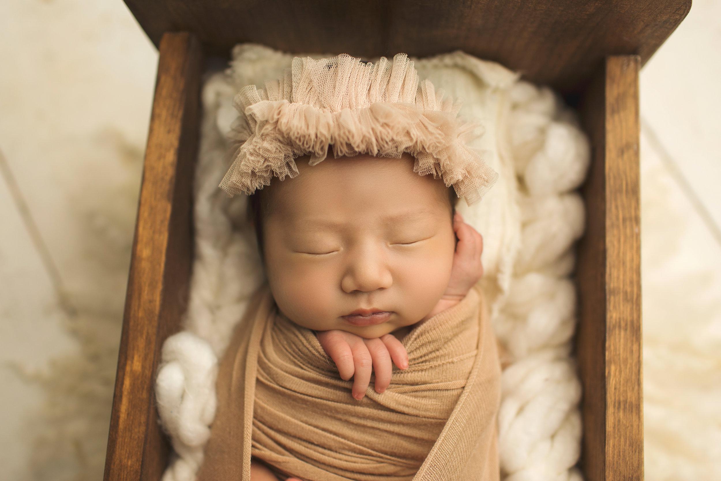 newborn in cradle wrapped in carmel brown 