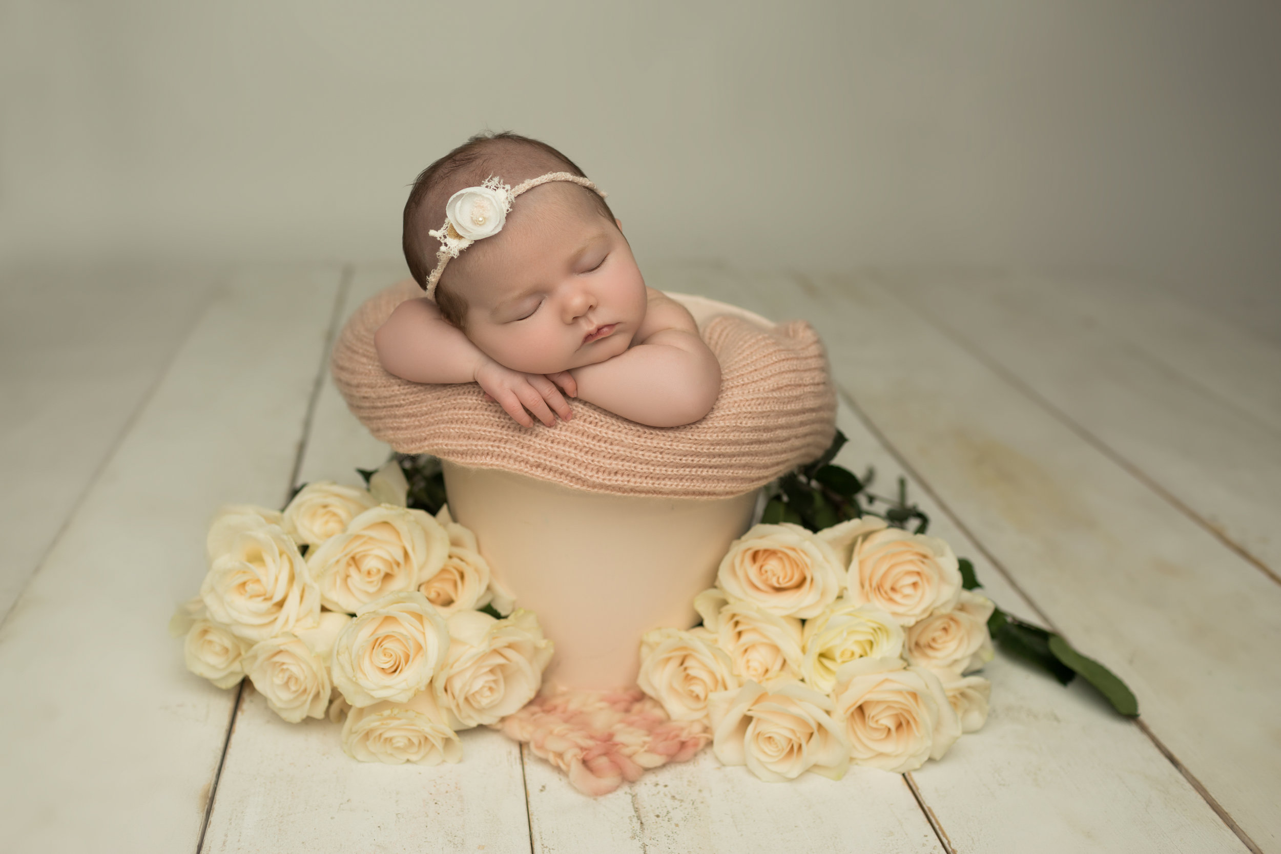 Baby girl in pink bucket surrounded by roses