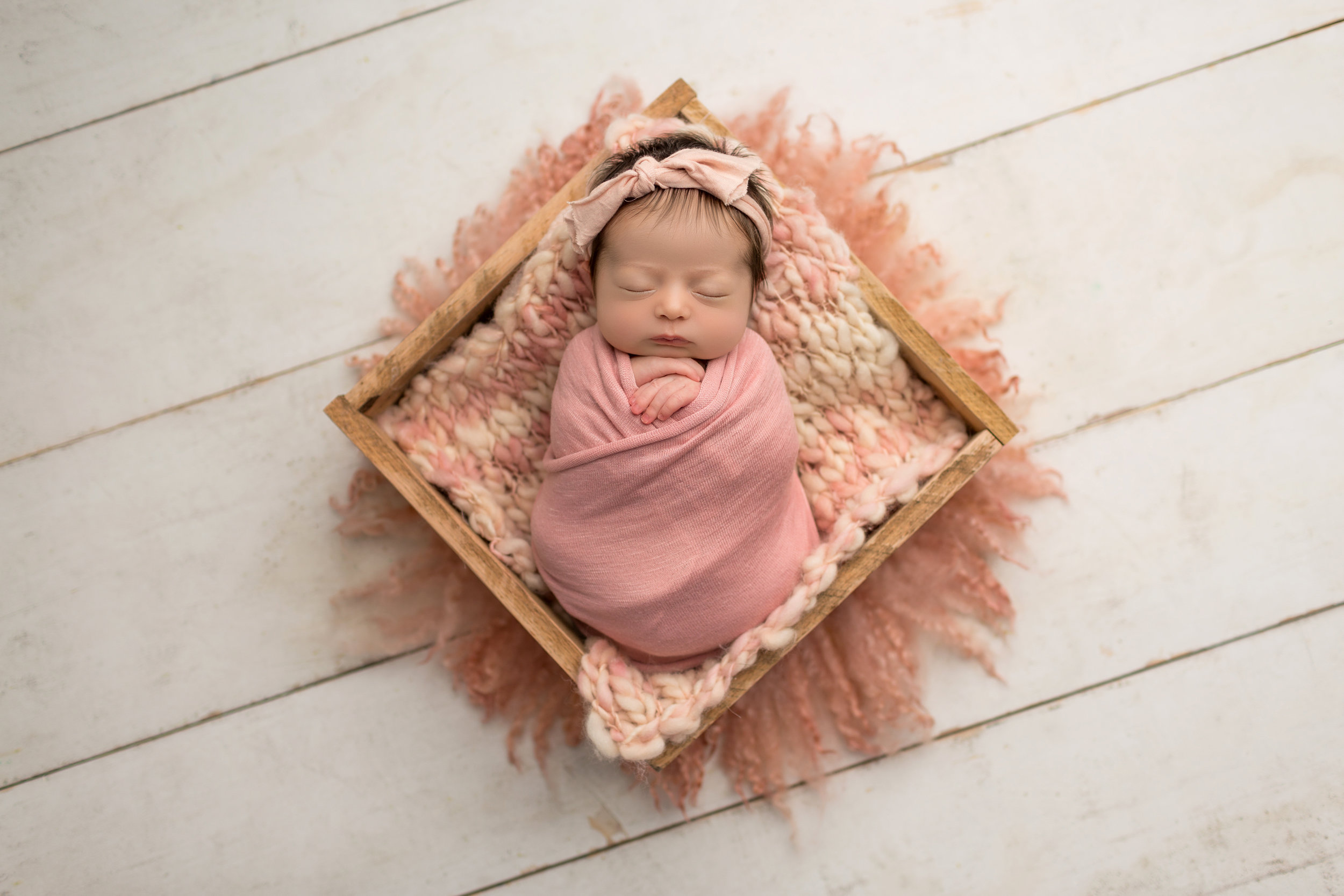 baby in box with bump blanket on top of pink fuzzy rug