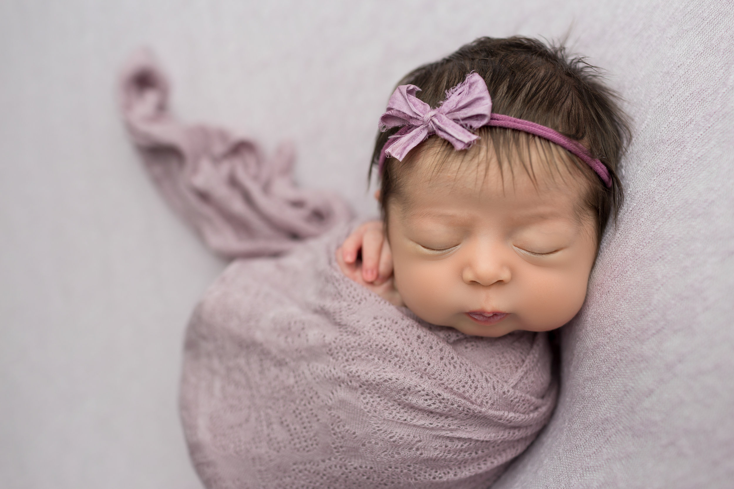 sleeping baby girl in lavender wrap with lavender bow