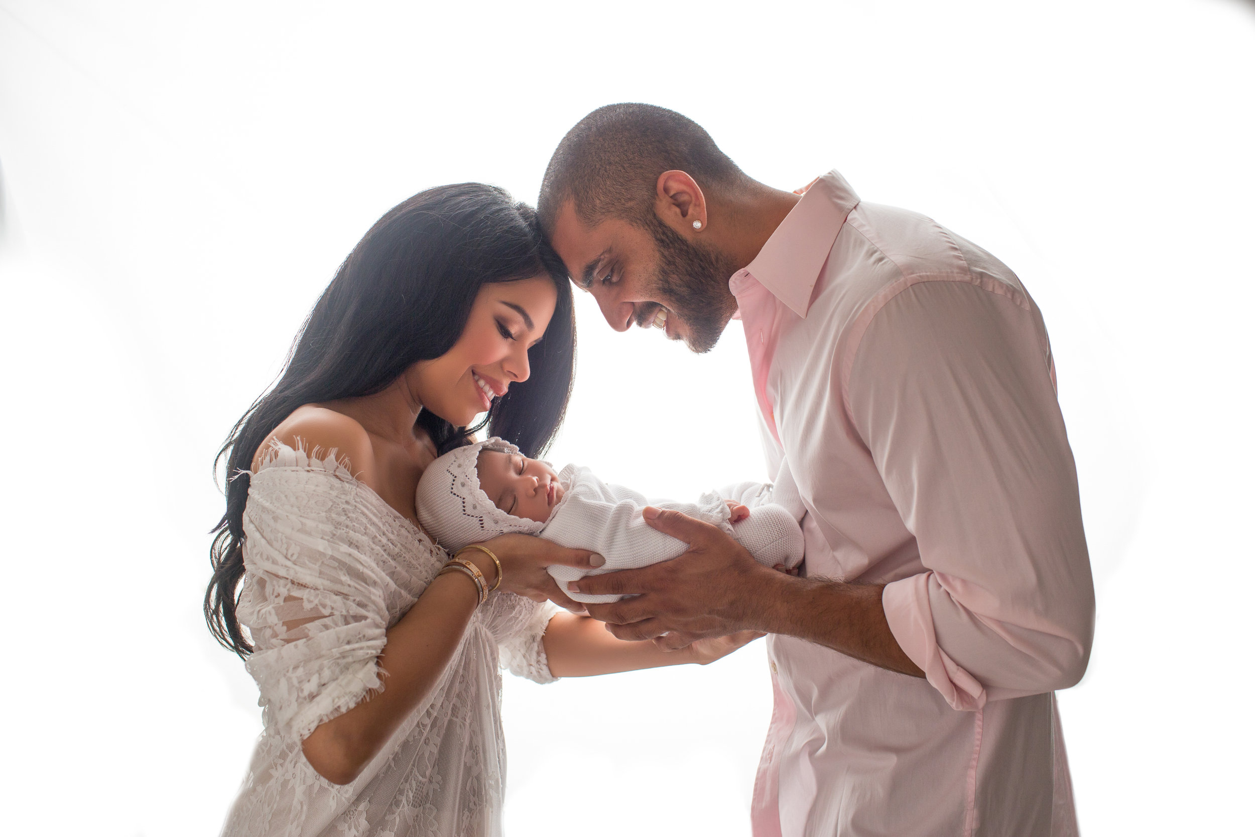 adoring couple dote on their newborn against a white light