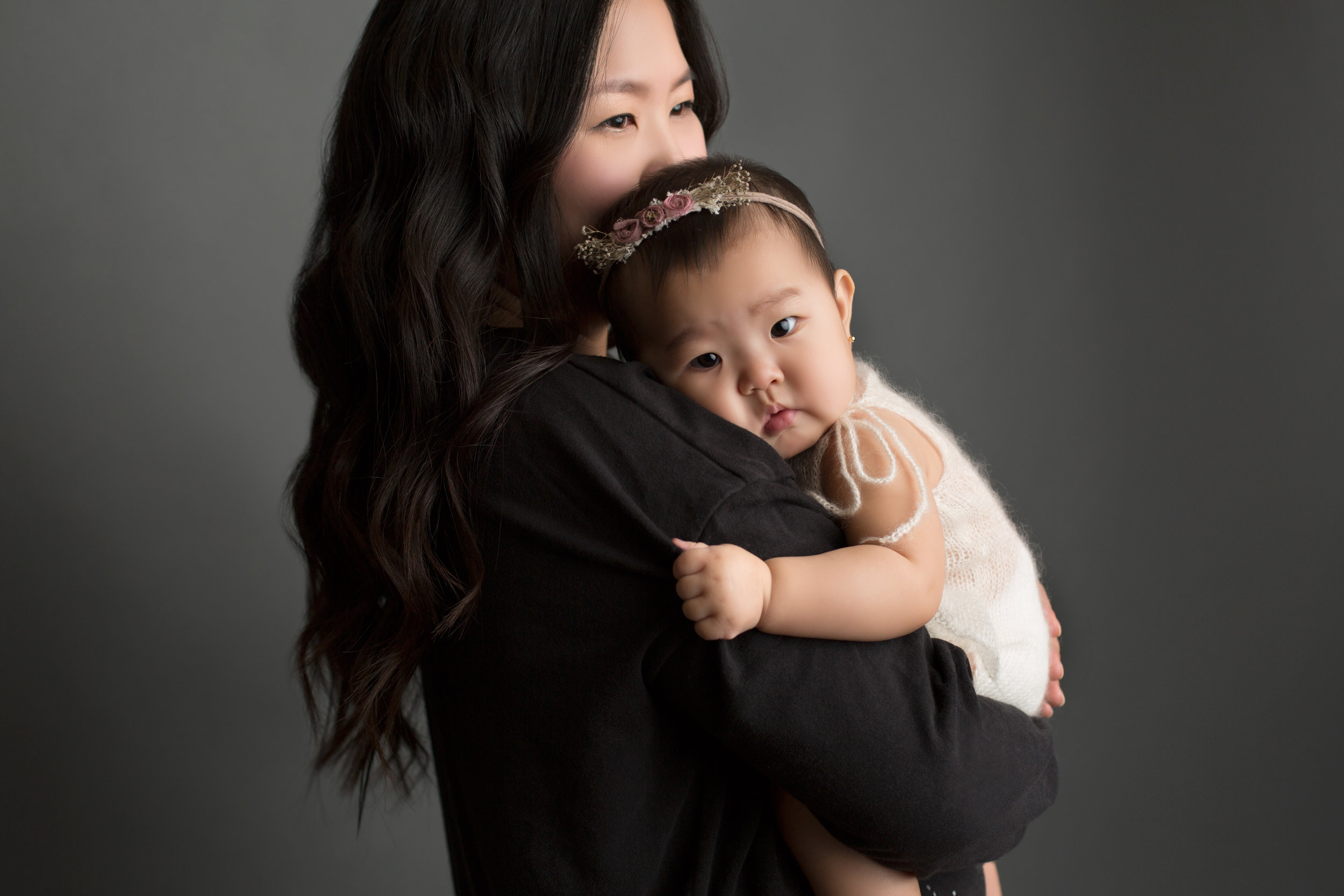 mom smiles while holding her 1 year old close