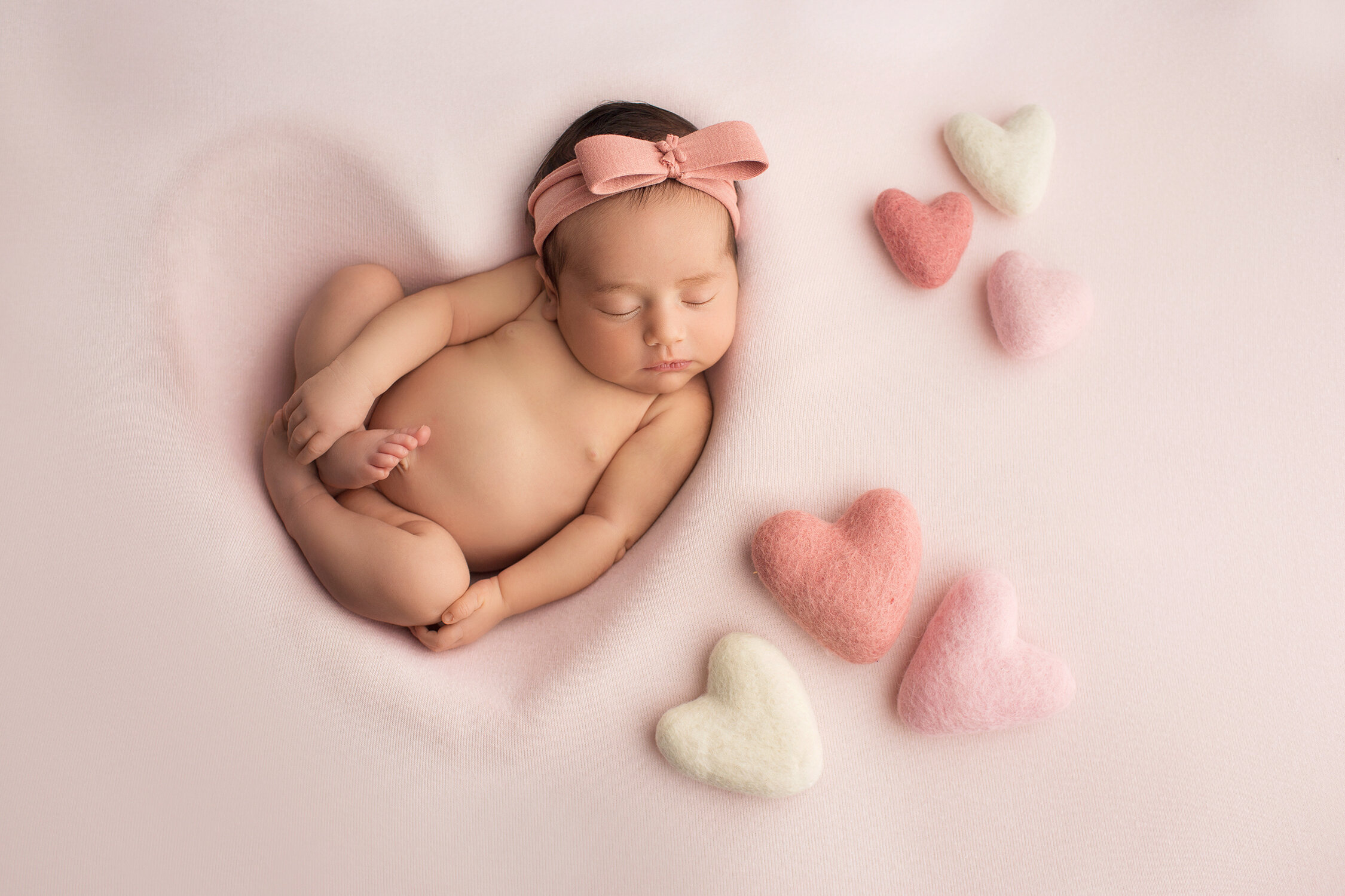 baby girl in a heart with felt hearts next to her
